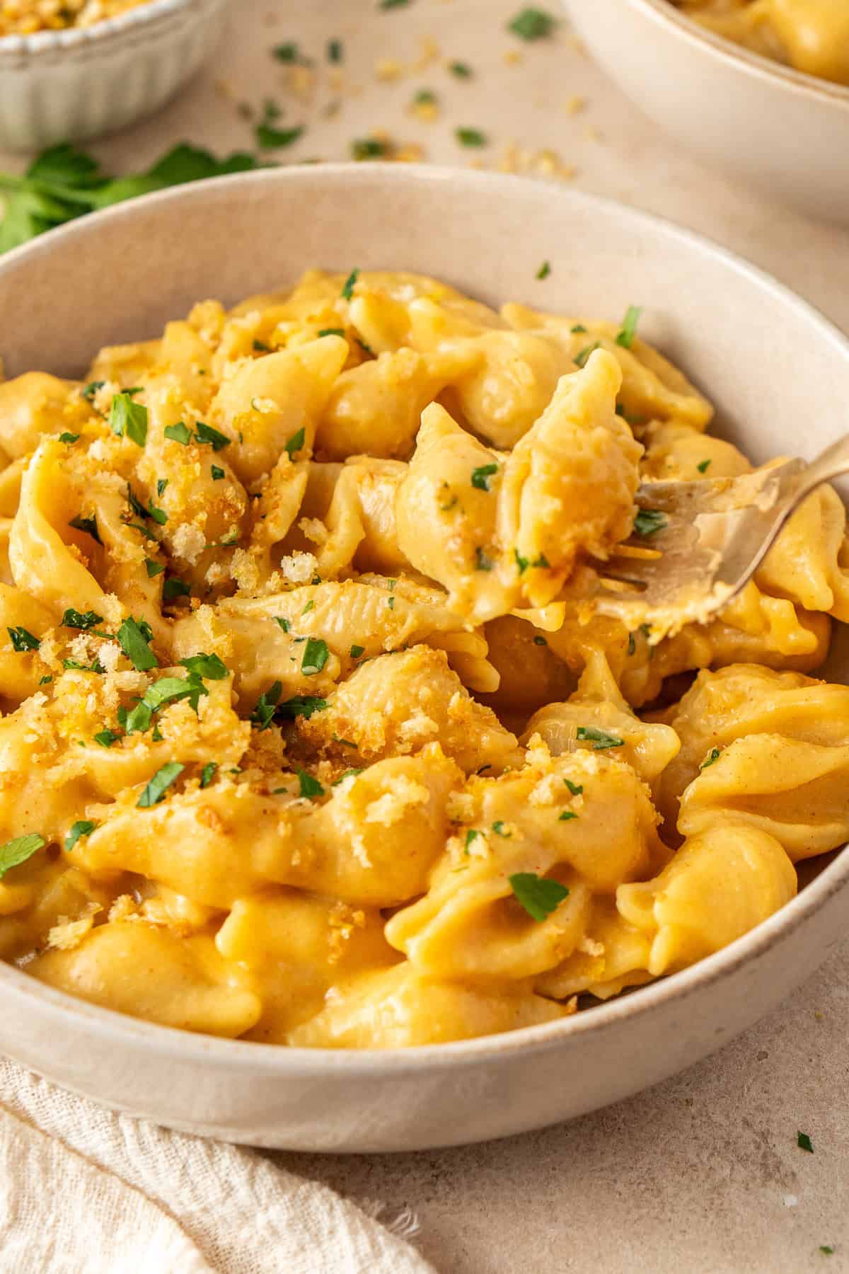 Close up of a fork taking a bite of the pasta from the bowl.
