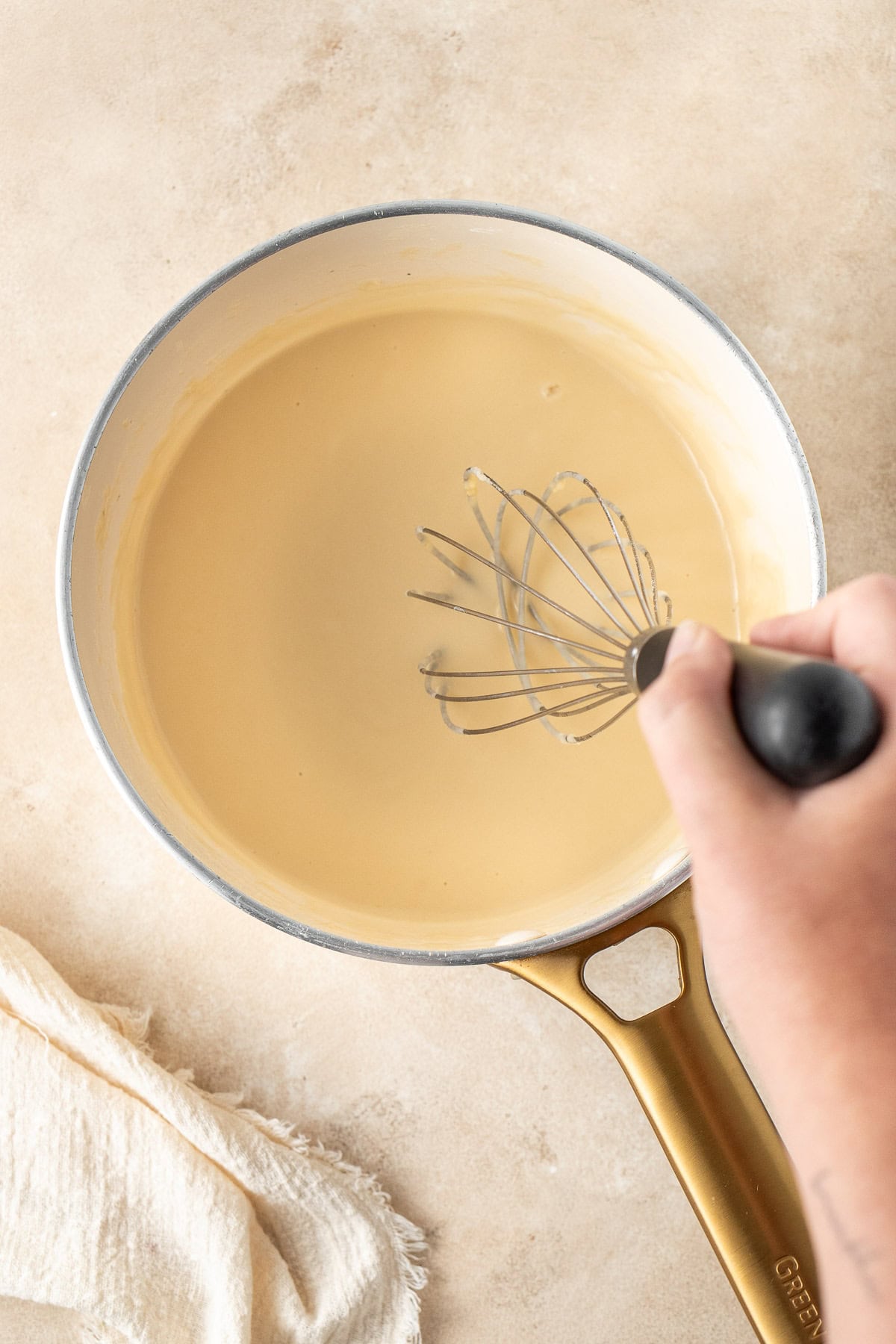 Whisking in the milk to make the white sauce.
