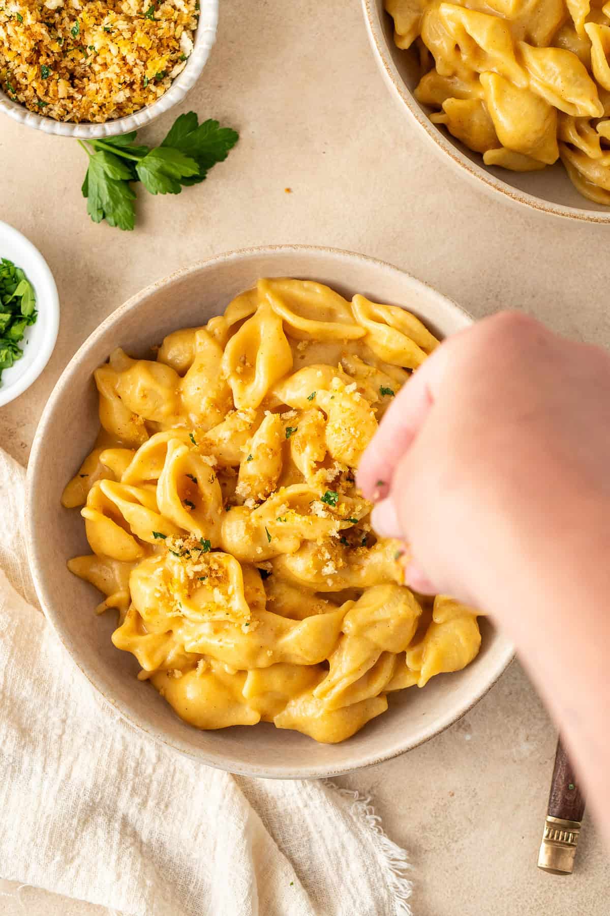 Sprinkling the breadcrumbs over the bowl of mac and cheese.