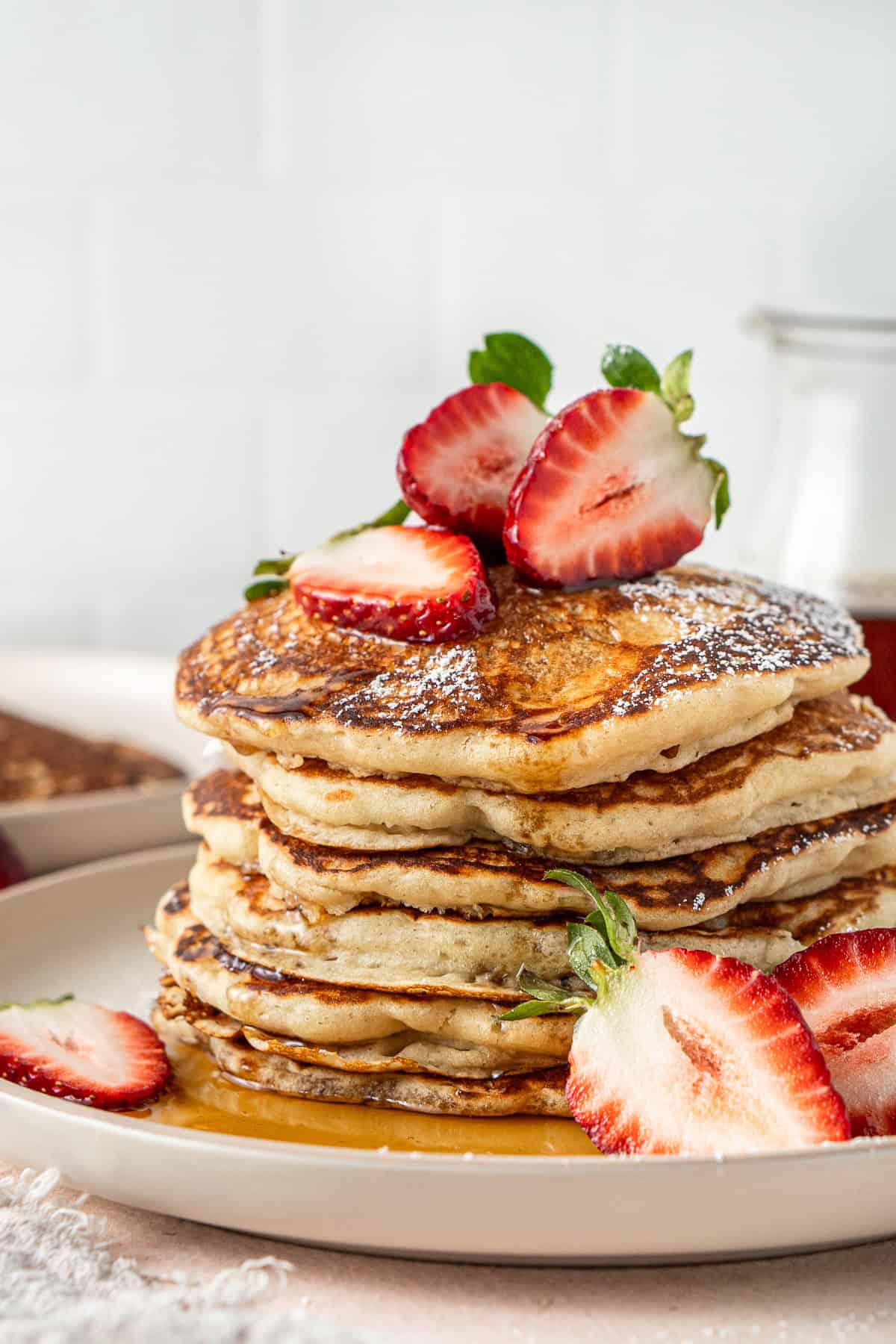 Close up of dairy free pancakes with strawberries and maple syrup.