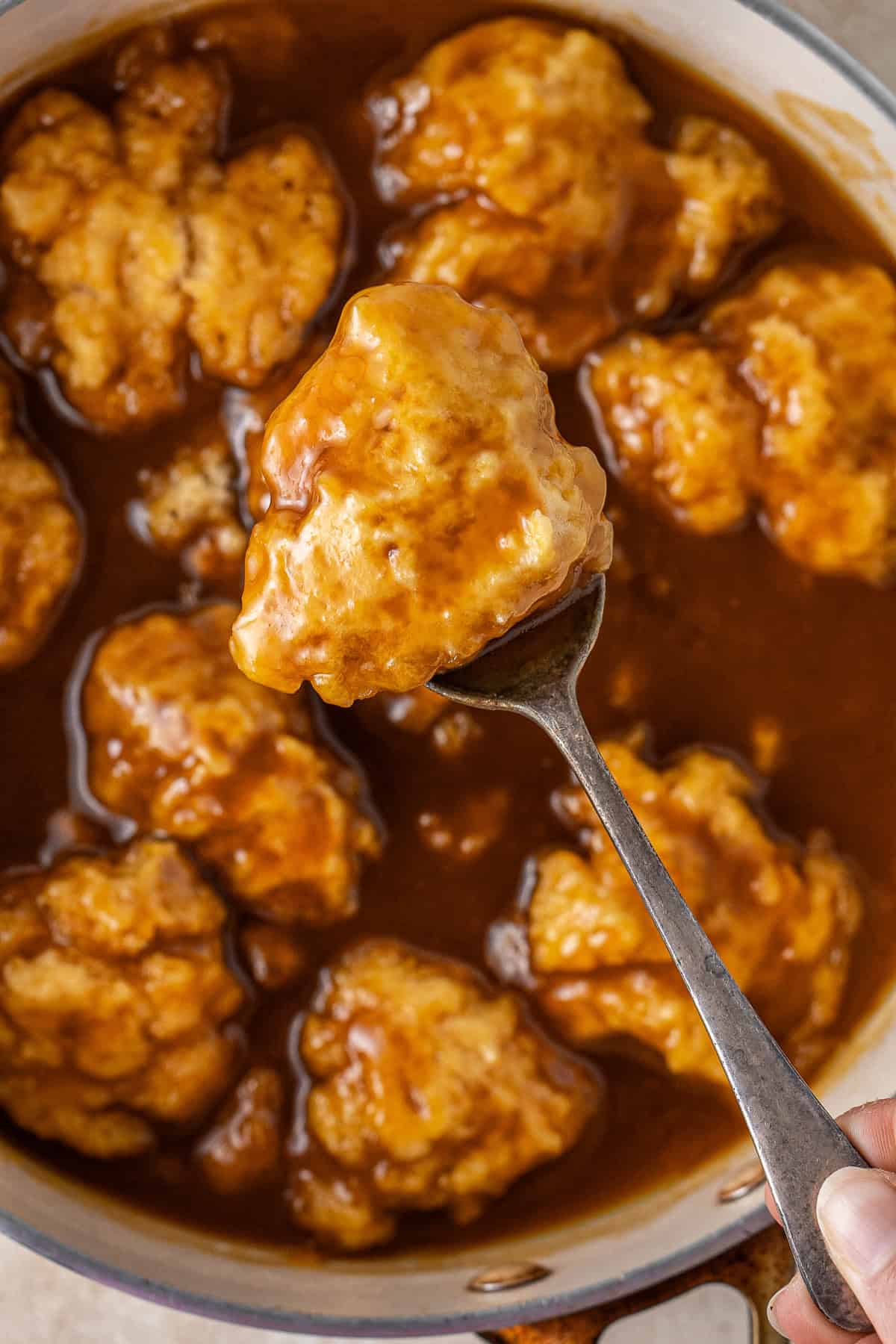 Close up of a spoon holding a golden syrup dumpling.