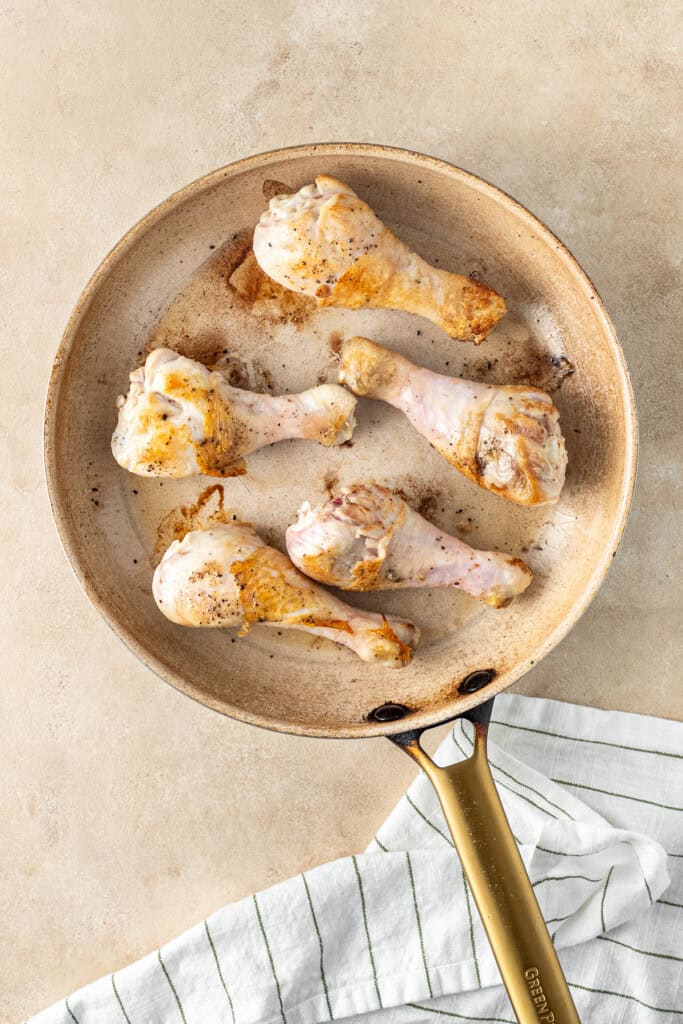 Browning the chicken drumsticks in a pan.
