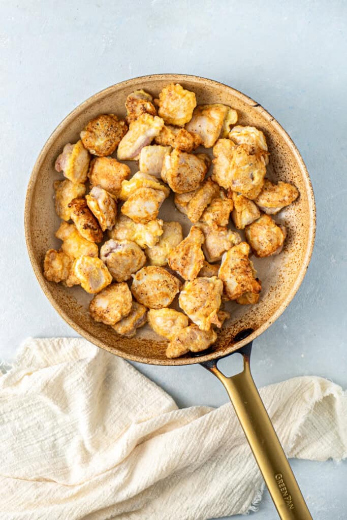 Adding the chicken pieces back to the frying pan.