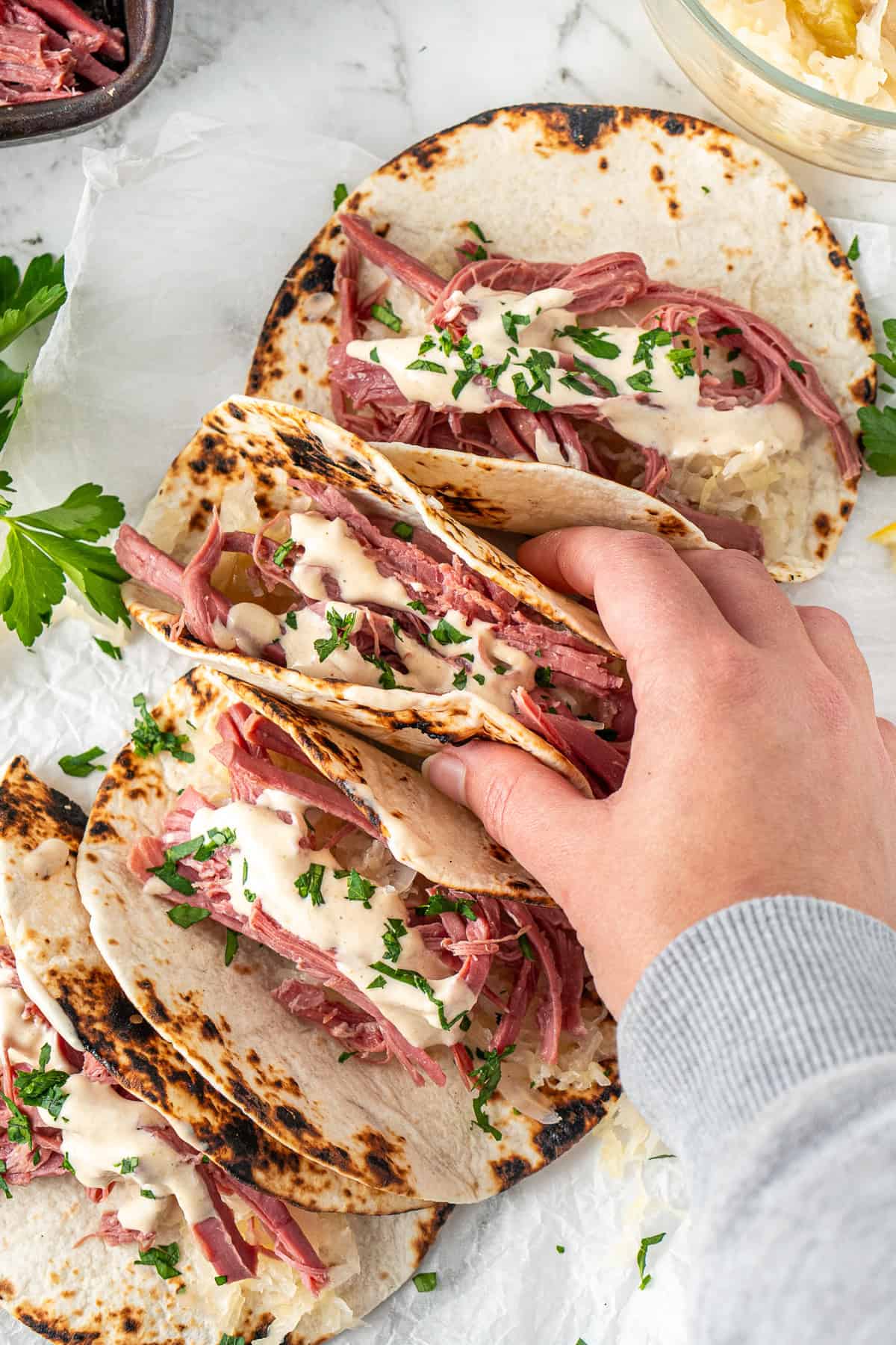 A hand picking up a corned beef taco.