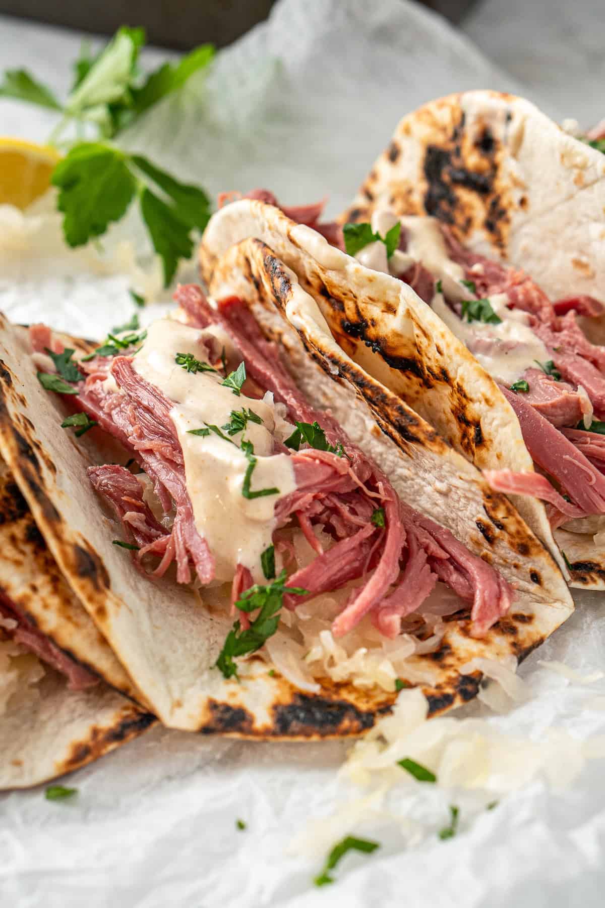 Close up of a corned beef taco with white sauce.