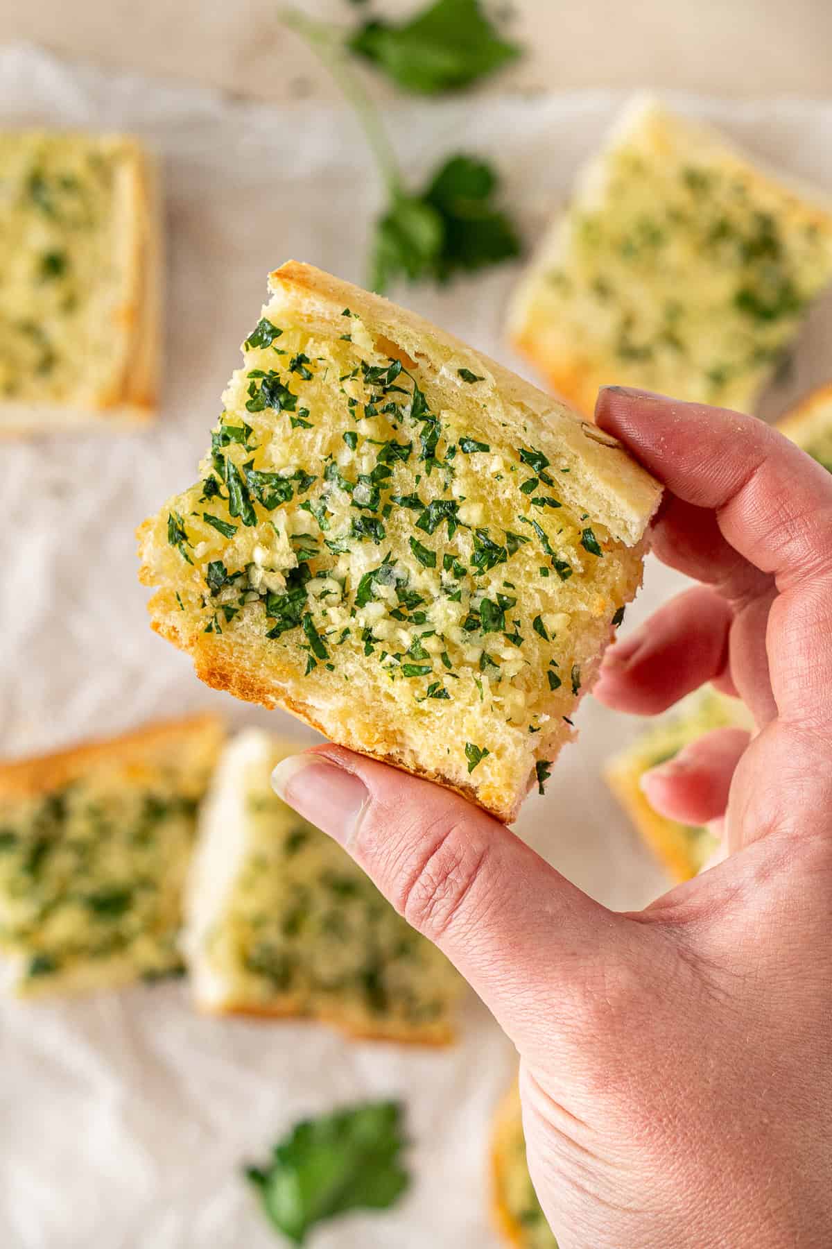 A hand holding up a piece of dairy free and vegan garlic bread.
