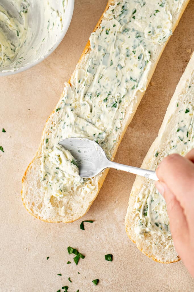 Spreading the garlic butter onto the bread.