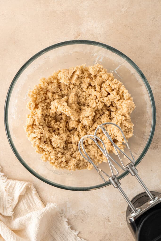 The cookie dough in a mixing bowl with electric beaters.