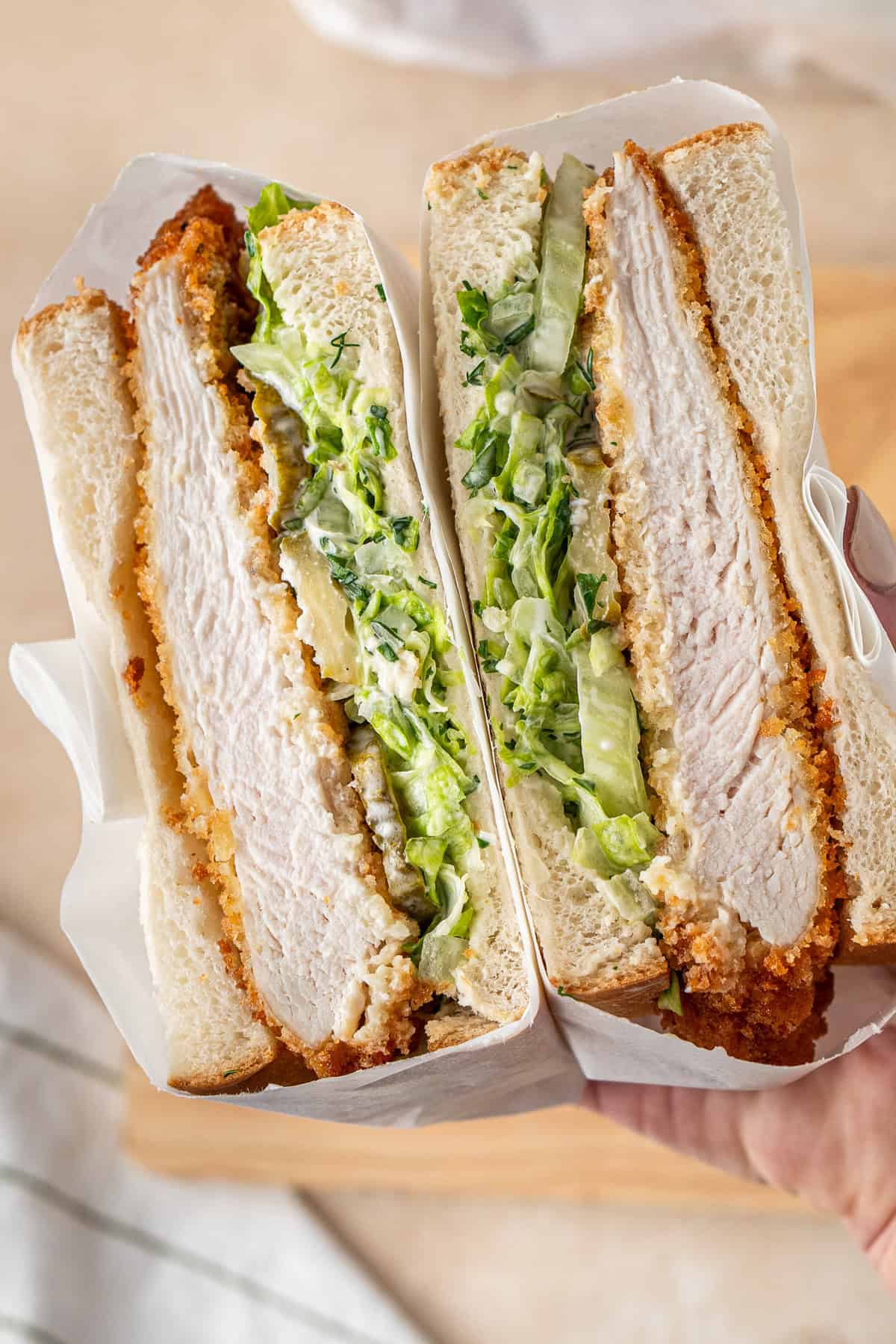 A chicken schnitzel sandwich with salad cut in half.