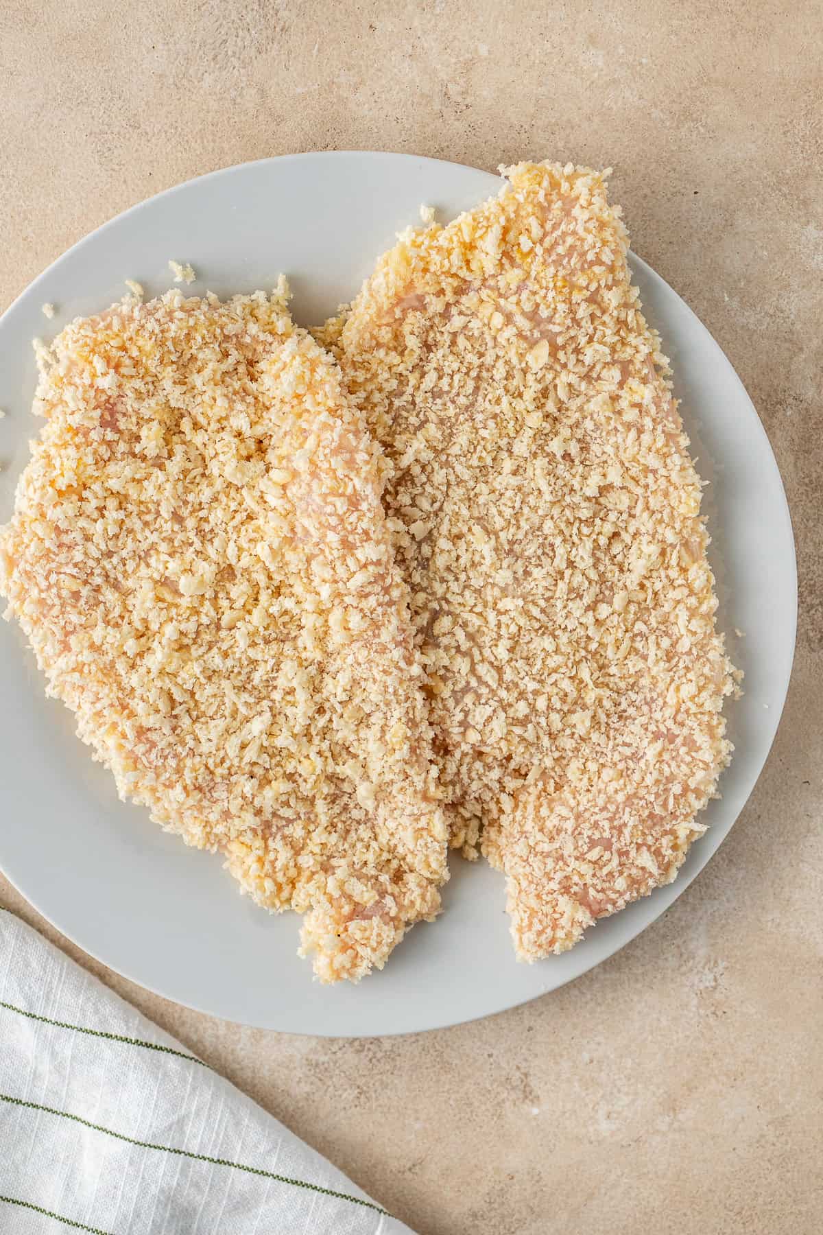 Chicken schnitzels crumbed on a plate.