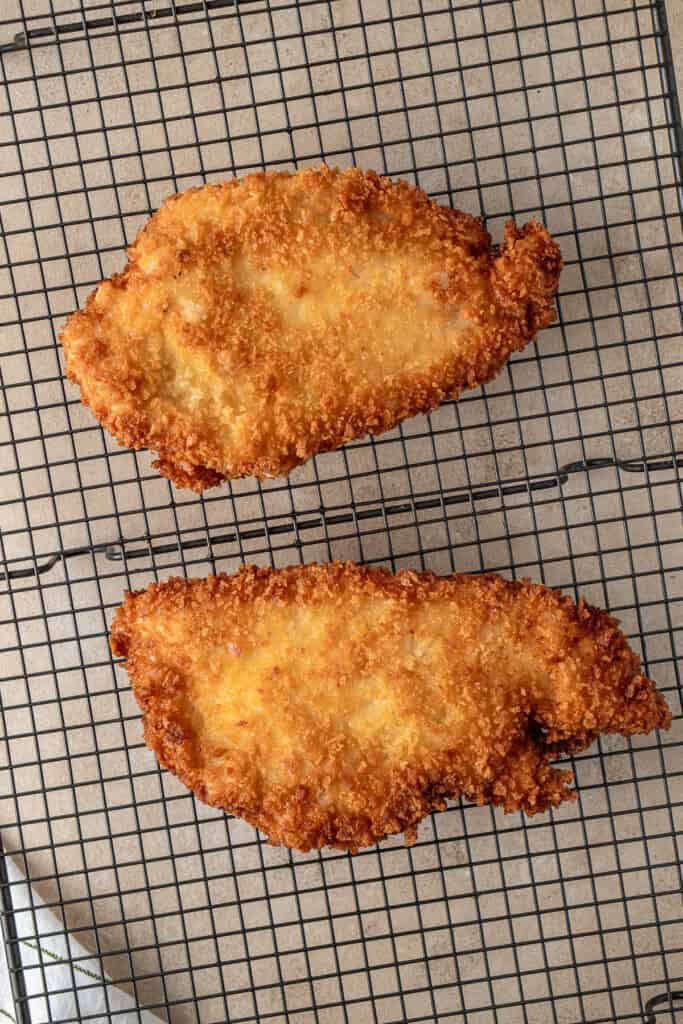 The fried chicken schnitzel on a cooling rack.