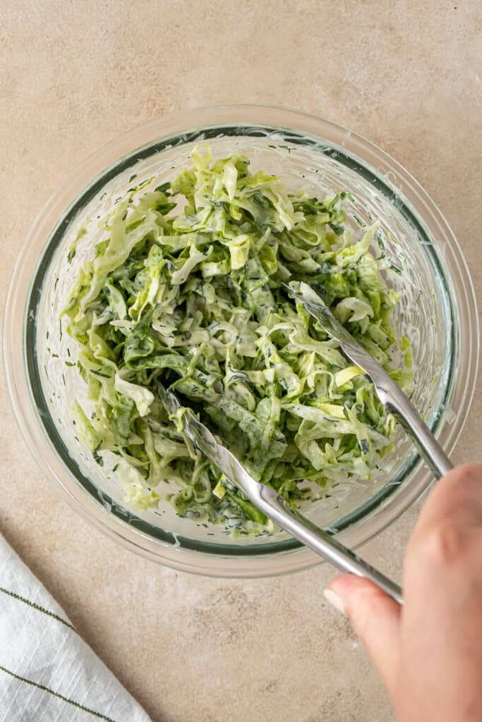 Tossing the lettuce with the mayo.