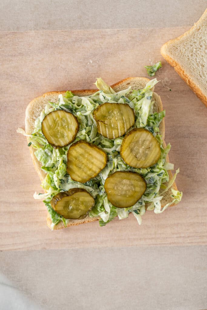 Assembling the salad on the sandwich.