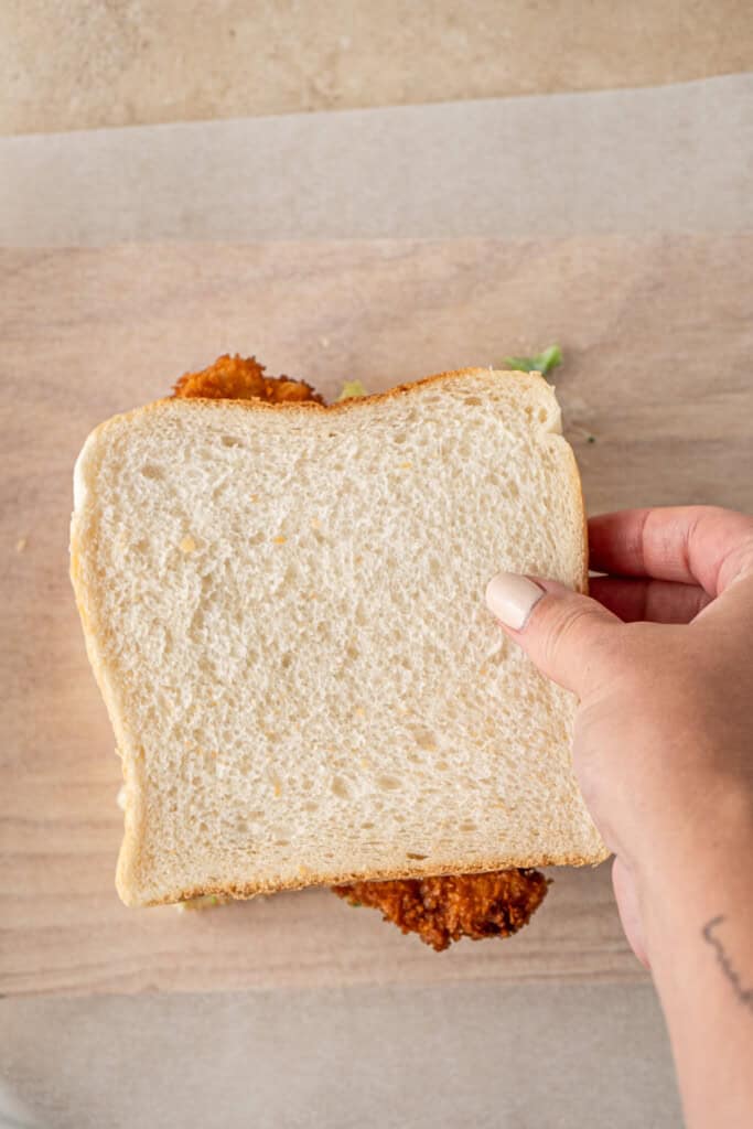 Placing the top slice of bread on the sandwich.