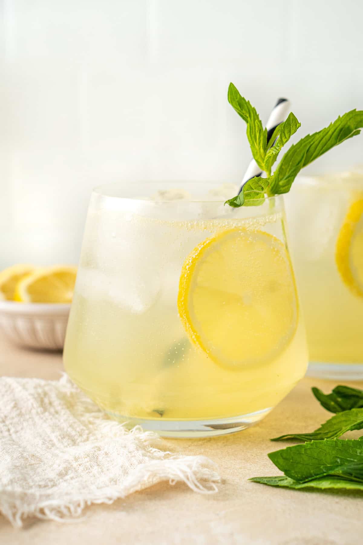 A close up of a lemon spritz mocktail with lemon and mint.
