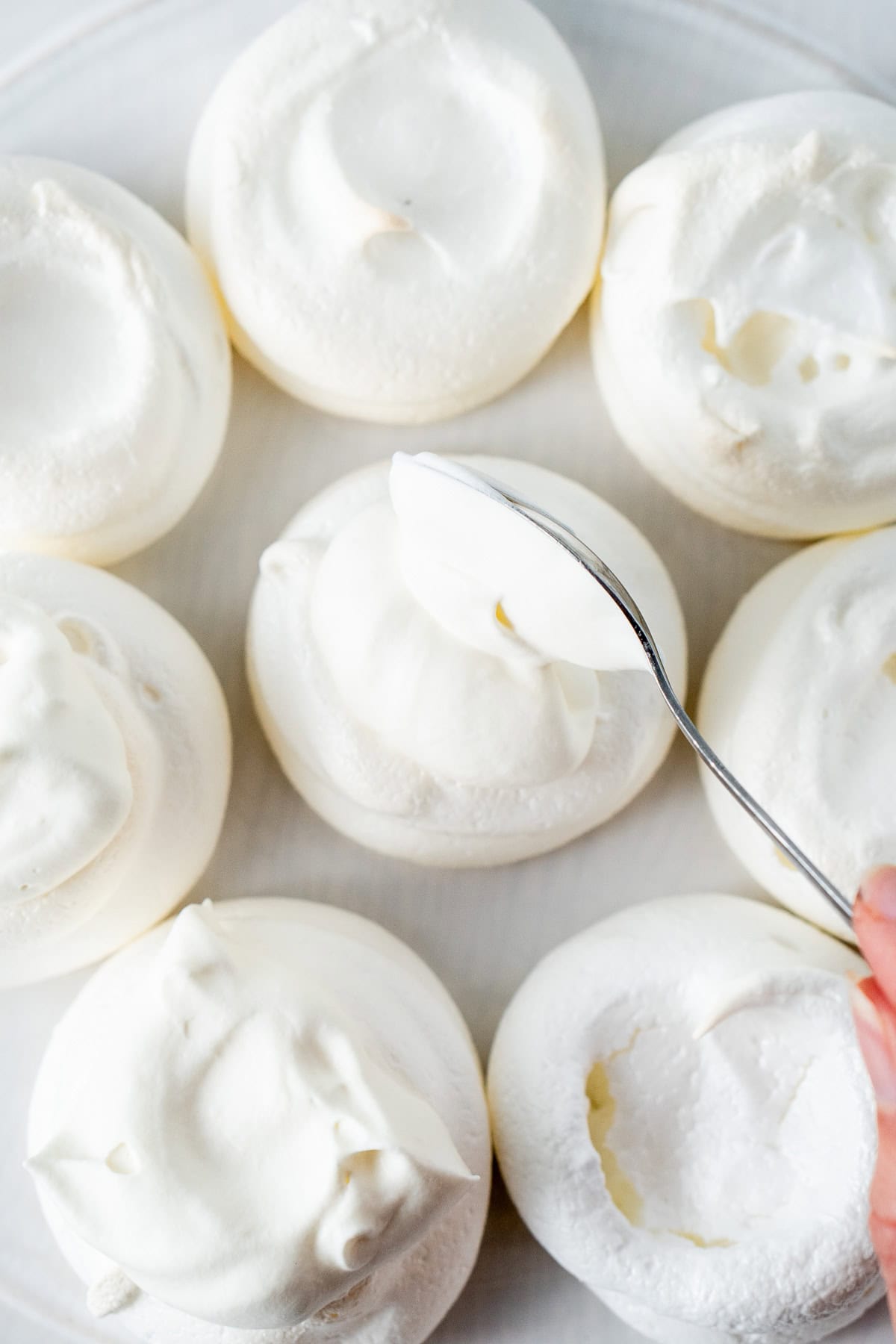 Spooning cream onto meringues.