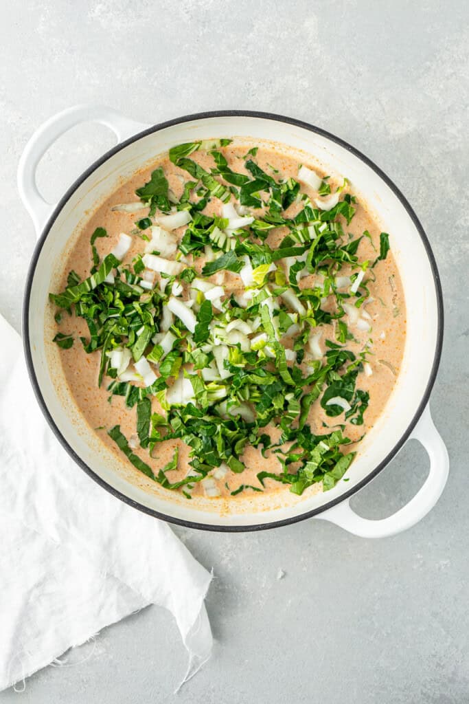 Adding the chopped bok choy to the casserole dish.