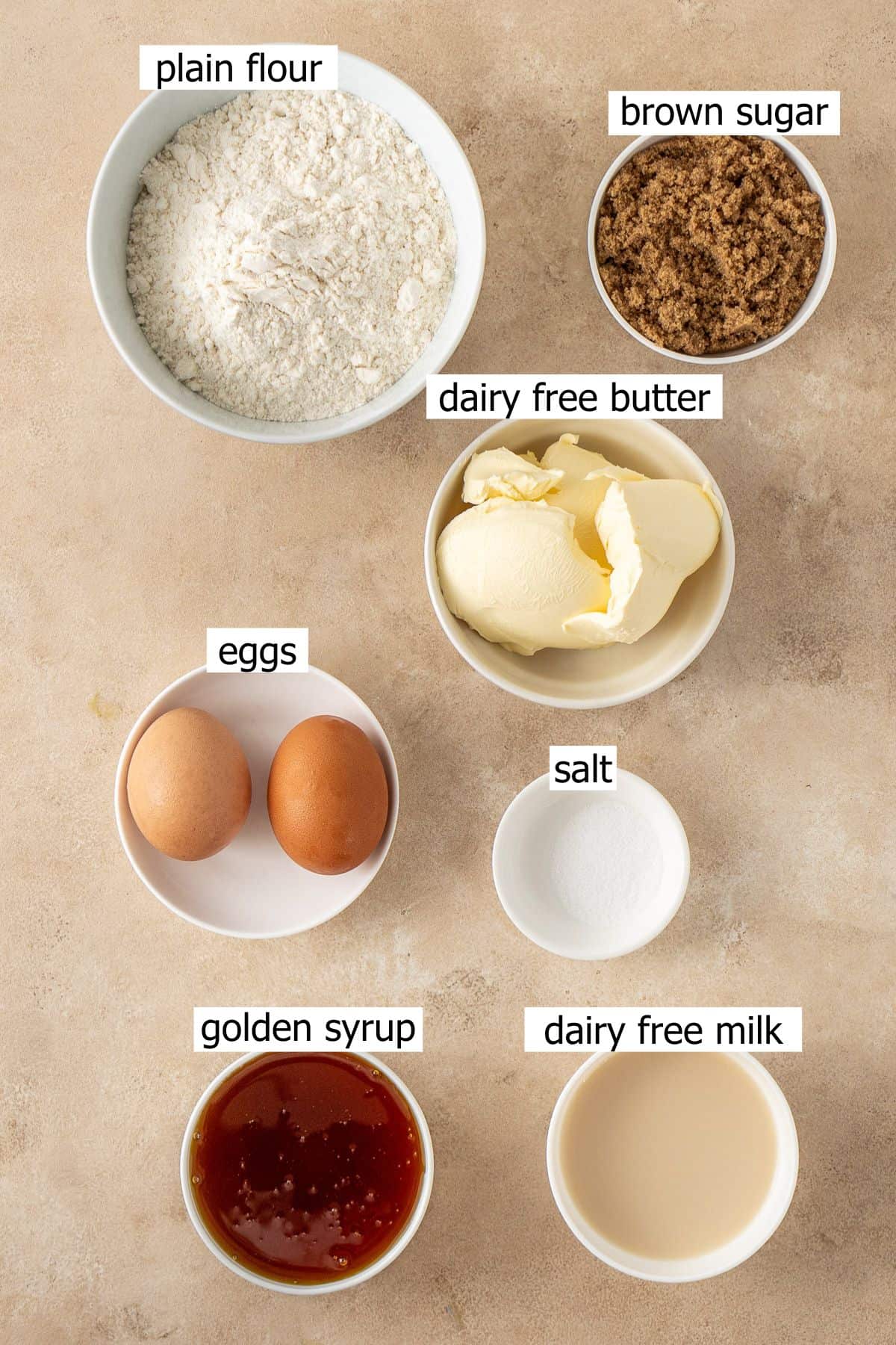 All ingredients needed to make golden syrup cake laid out in small bowls.