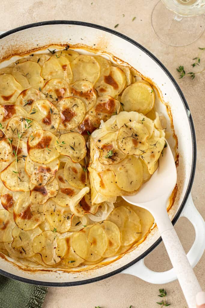 A spoon serving up the potatoes from the pan.