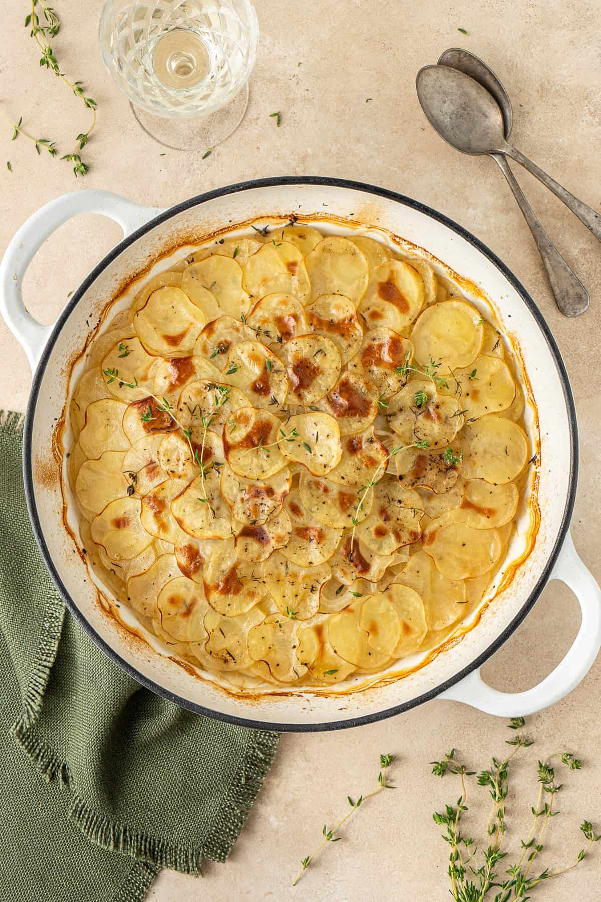 Boulangère potatoes in a pan served with fresh thyme.