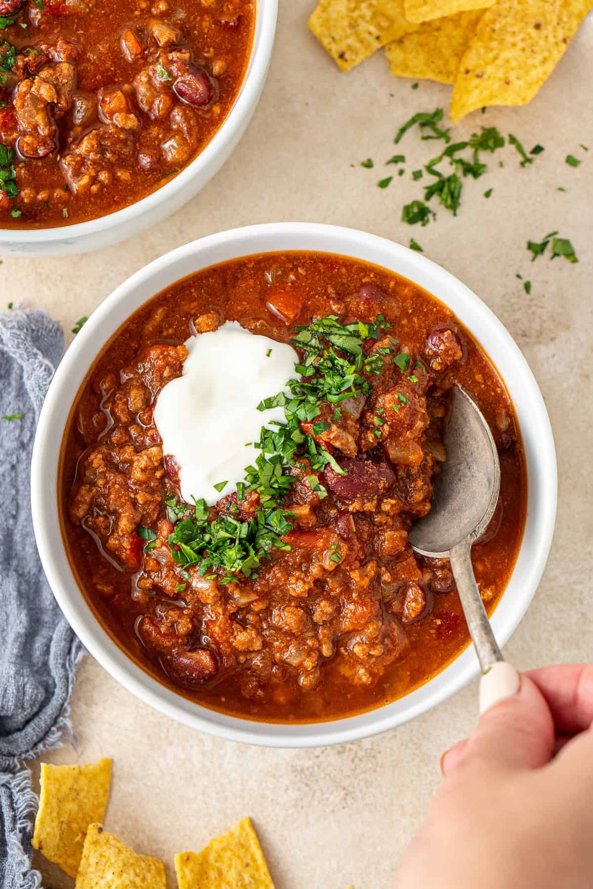 A hand taking a spoonful of the chilli from the bowl. 