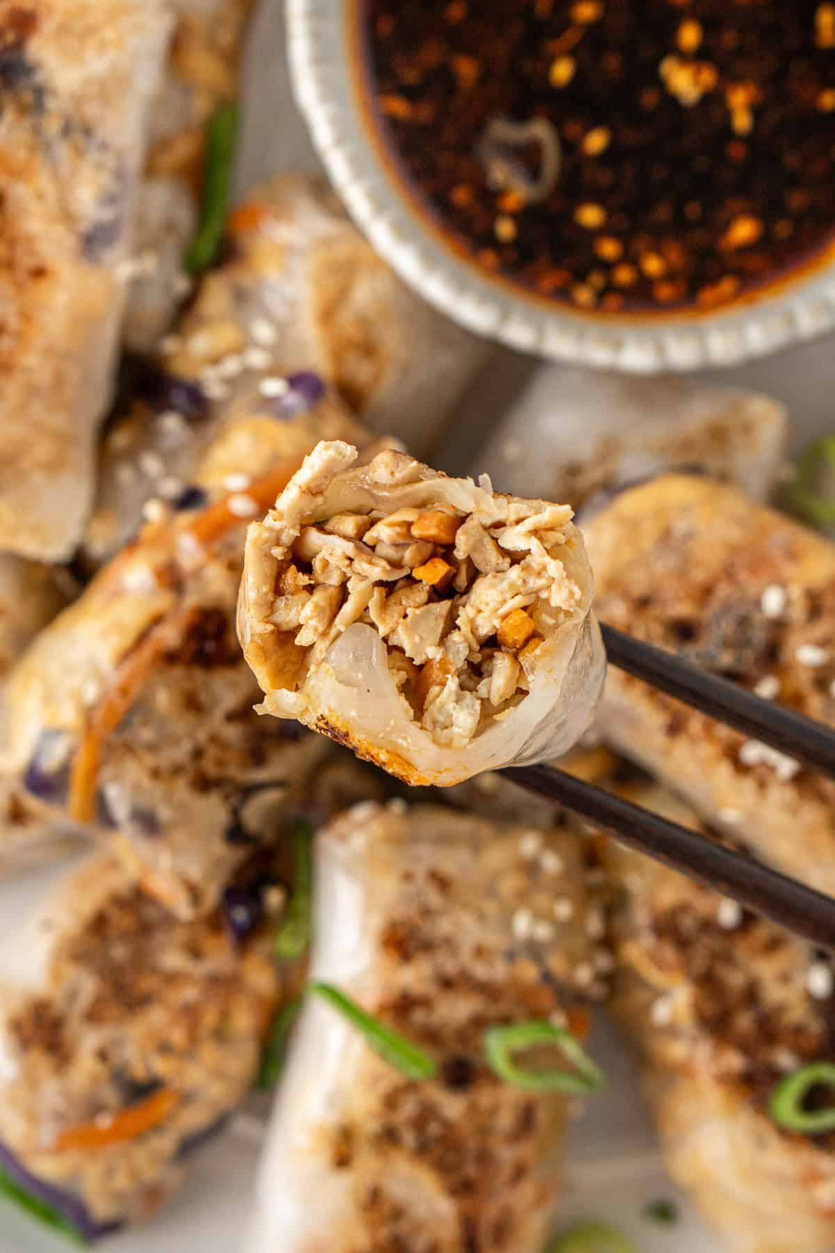 Chopsticks holding a dumpling with a bite taken showing the filling.