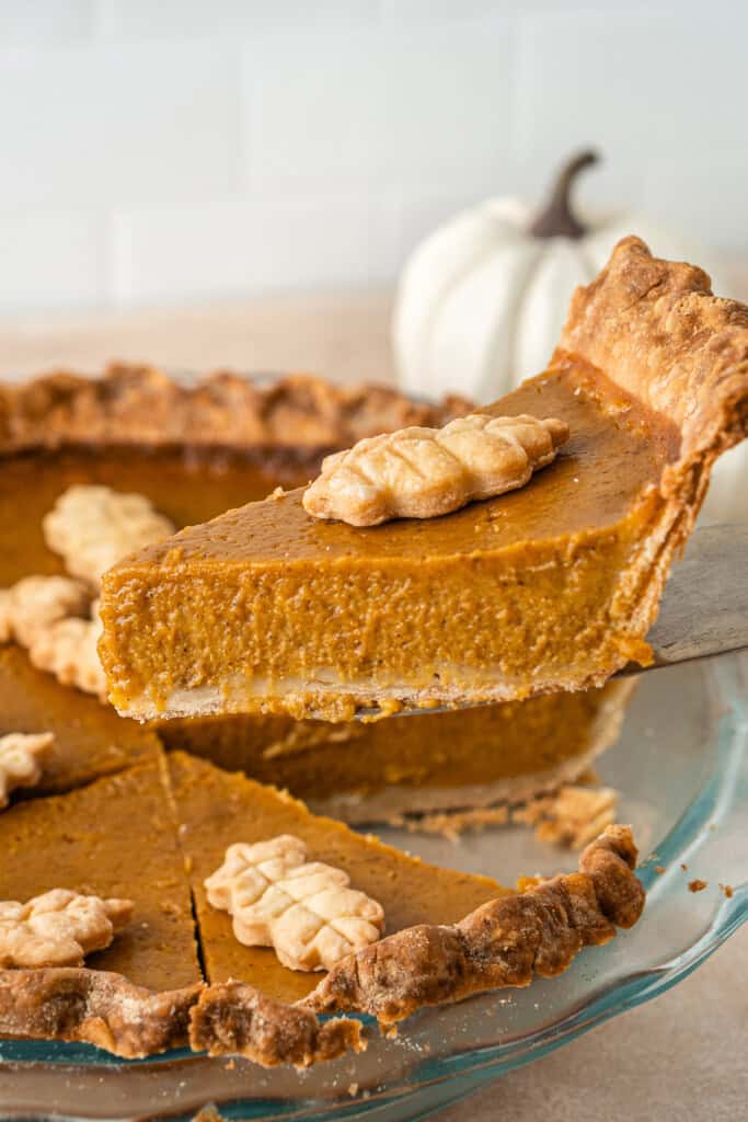 Lifting a slice of pumpkin pie from the dish.