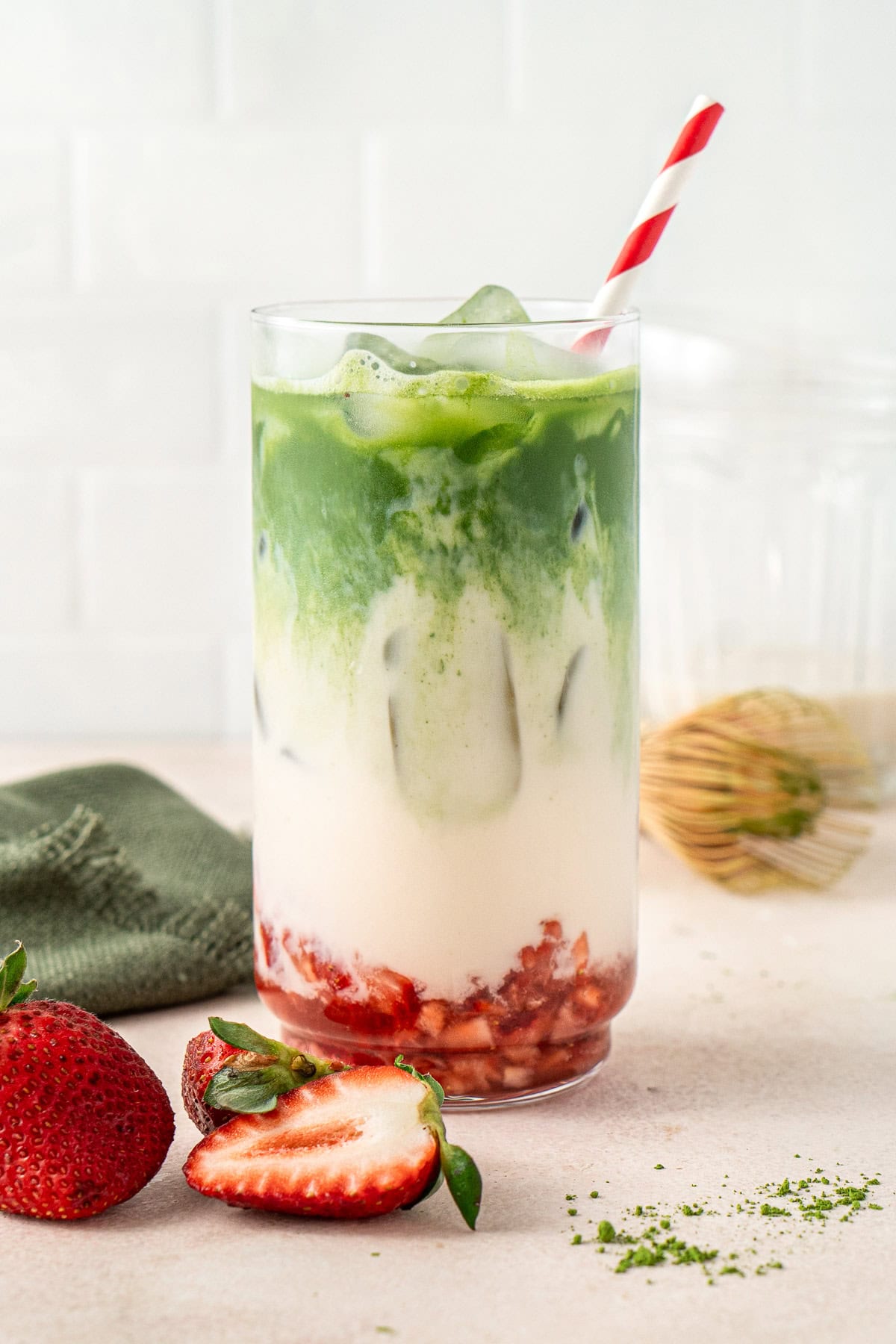 A strawberry matcha latte in a glass showing the three layers.