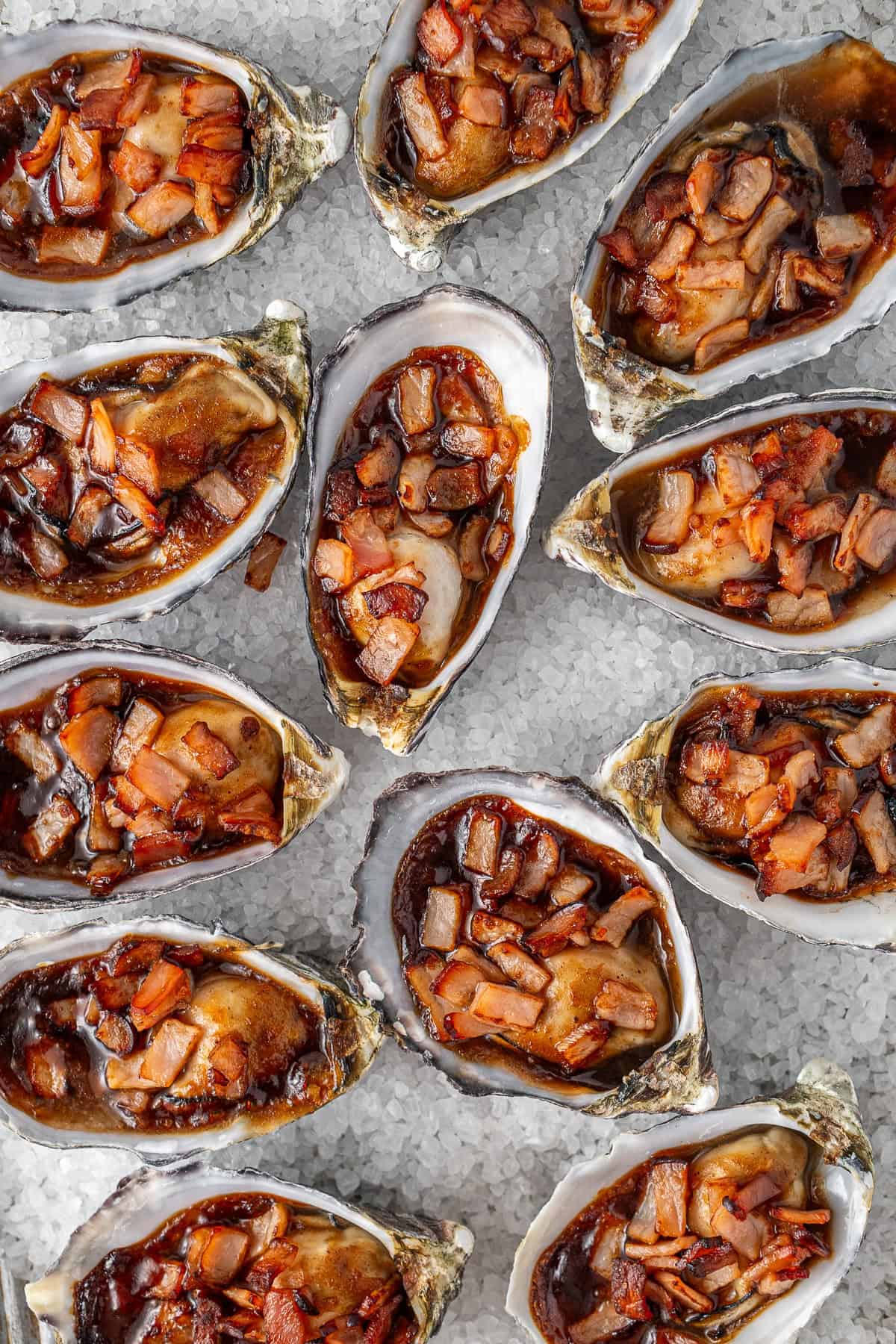The cooked oysters kilpatrick on a bed of rock salt.