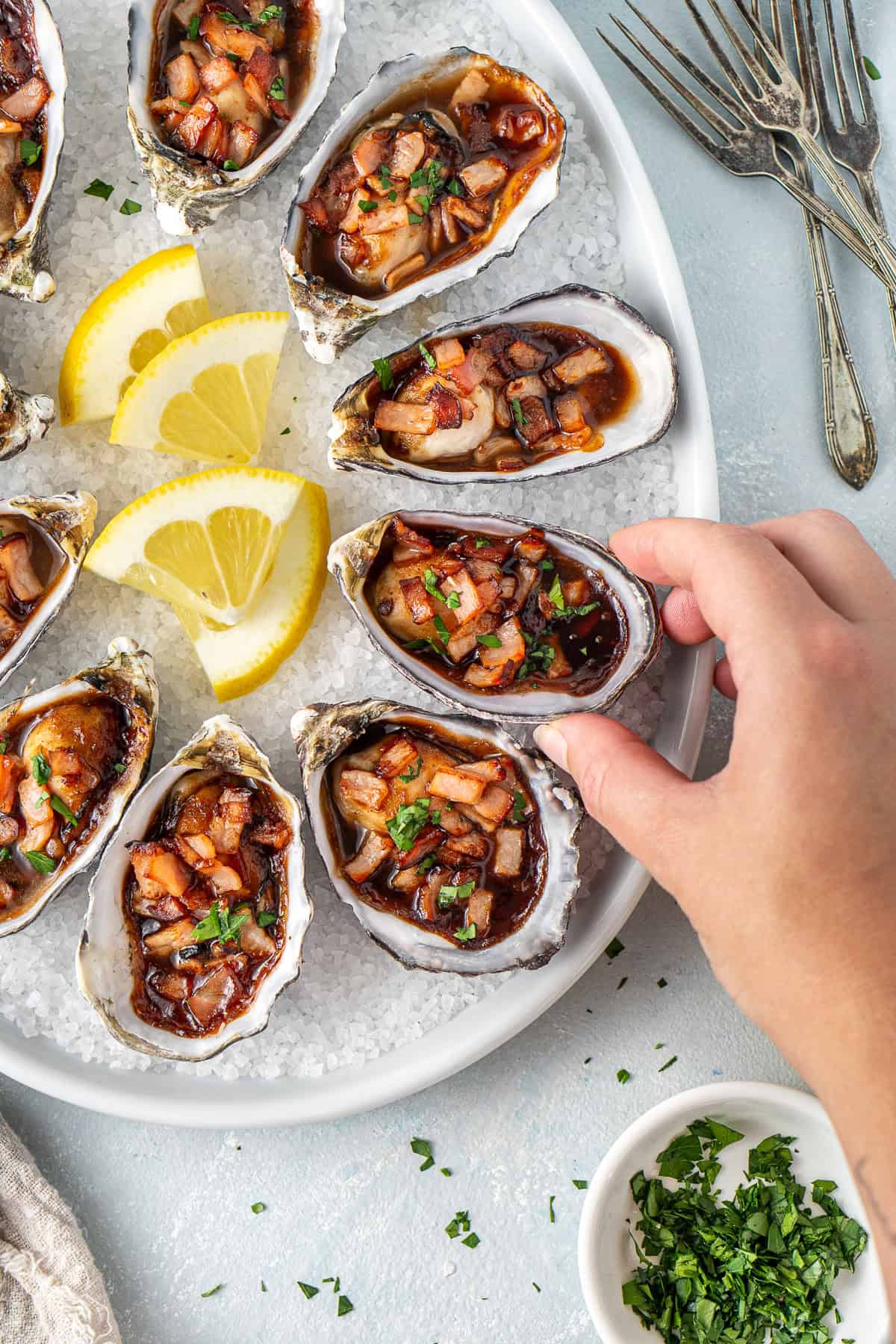 A hand picking up an oyster from the platter.