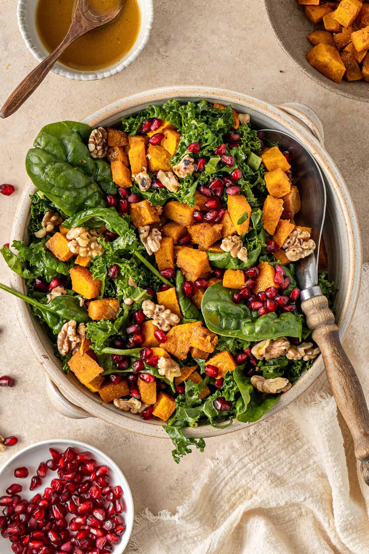 The roast pumpkin salad in a bowl with a serving spoon.