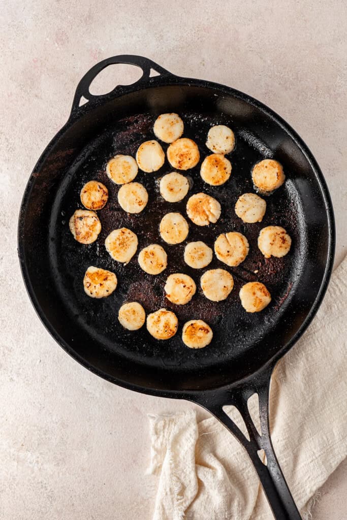 Searing the scallops in a pan.