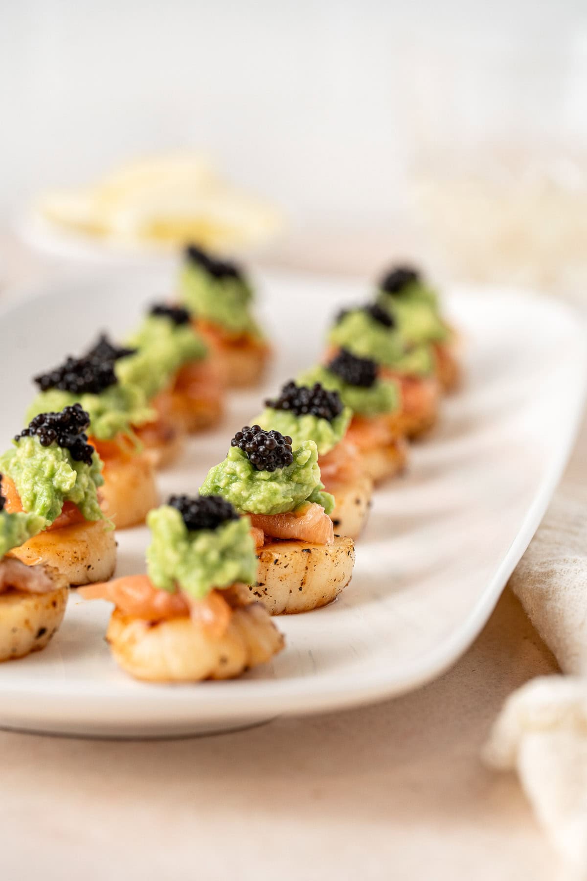 A plate of seared scallops with salmon and caviar.