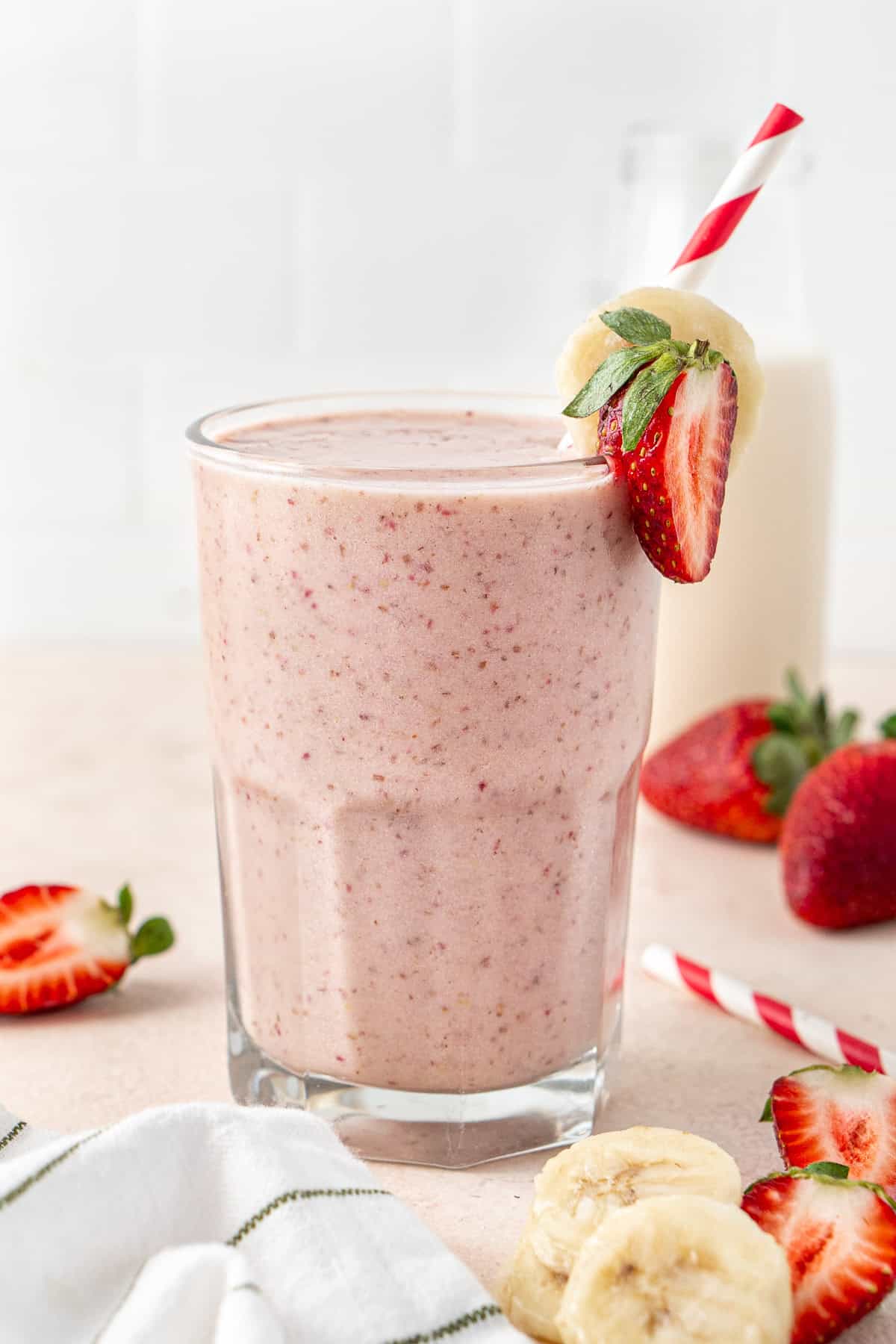 Close up of a strawberry banana smoothie in a glass with a straw.