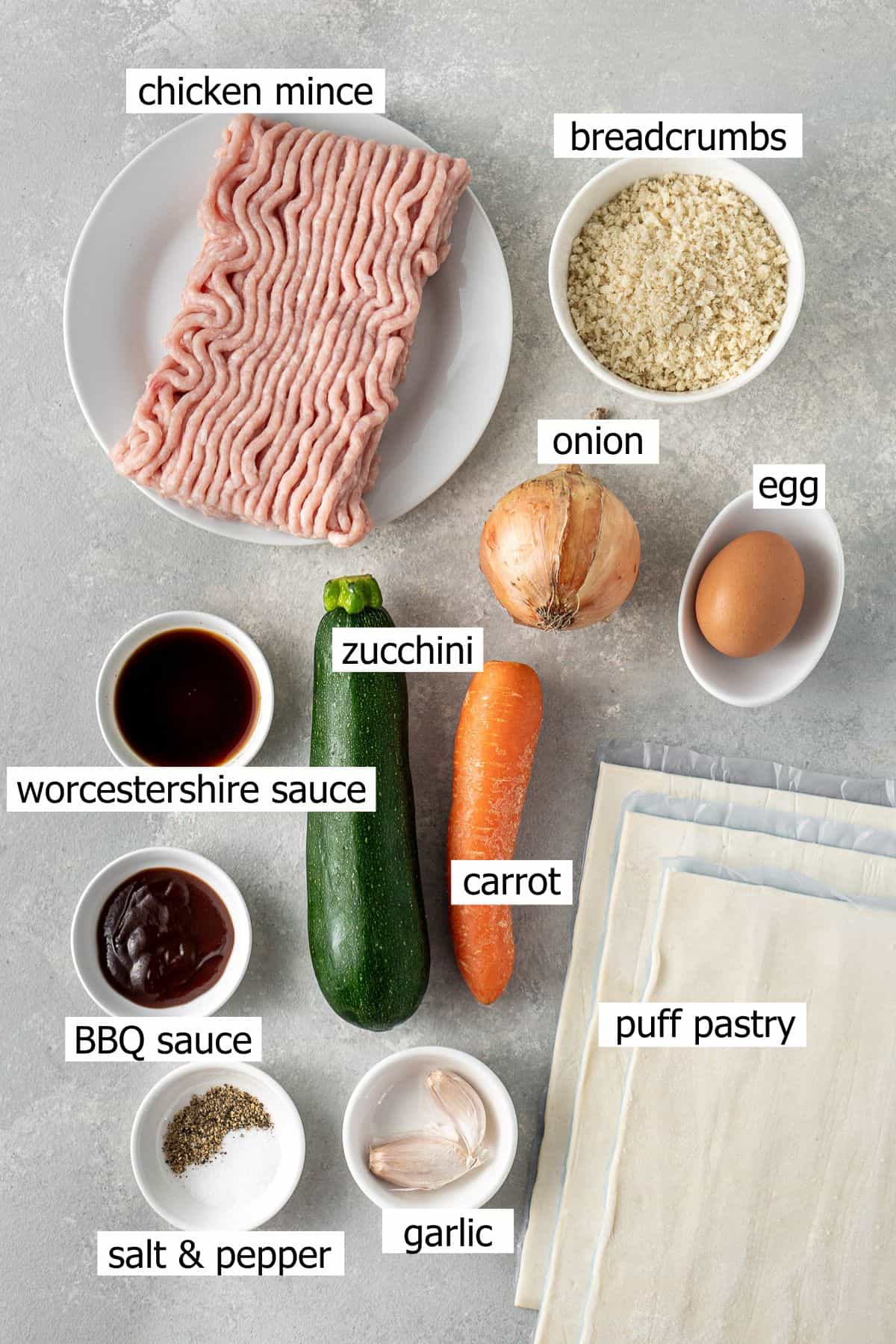 All ingredients needed to make chicken sausage rolls laid out in bowls.