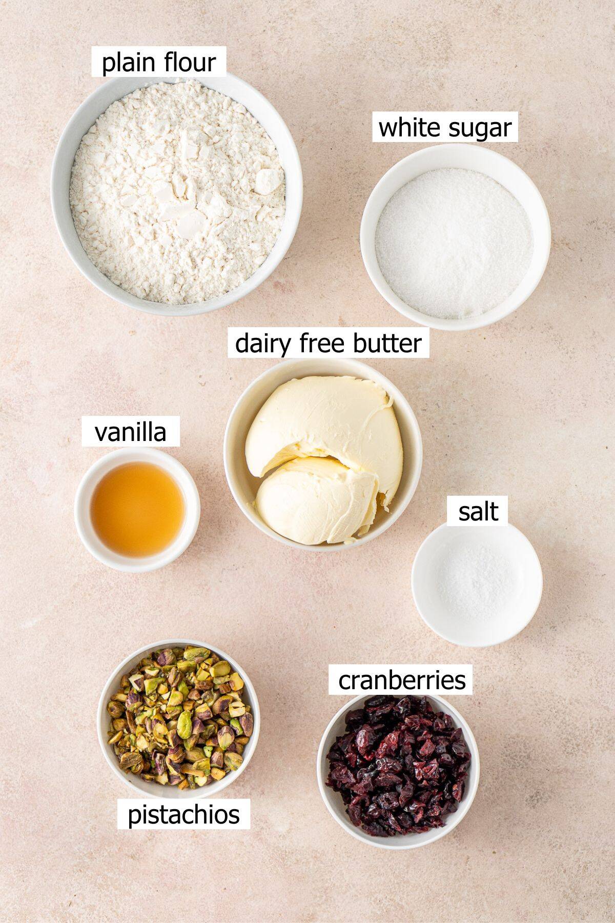 All ingredients needed to make pistachio cranberry shortbread cookies laid out in small bowls.