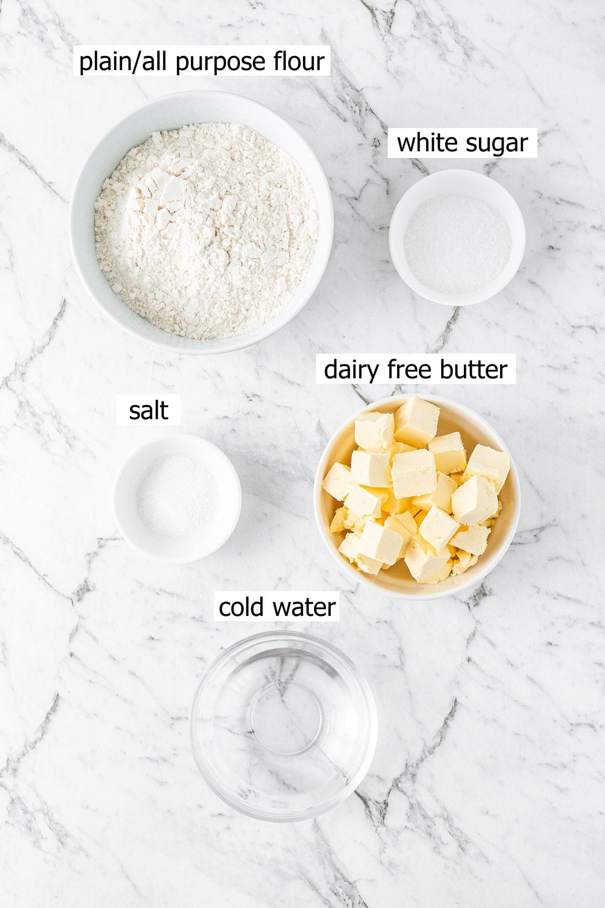 All the ingredients needed to make dairy free pie crust laid out in small bowls.
