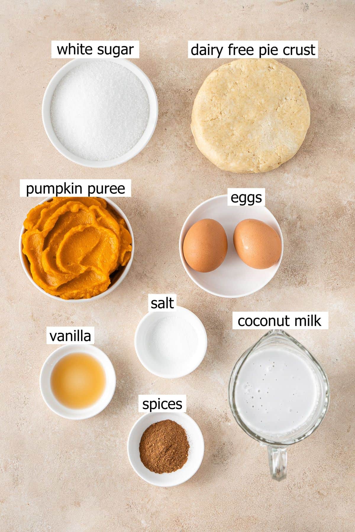All ingredients needed to make a dairy free pumpkin pie laid out in small bowls.