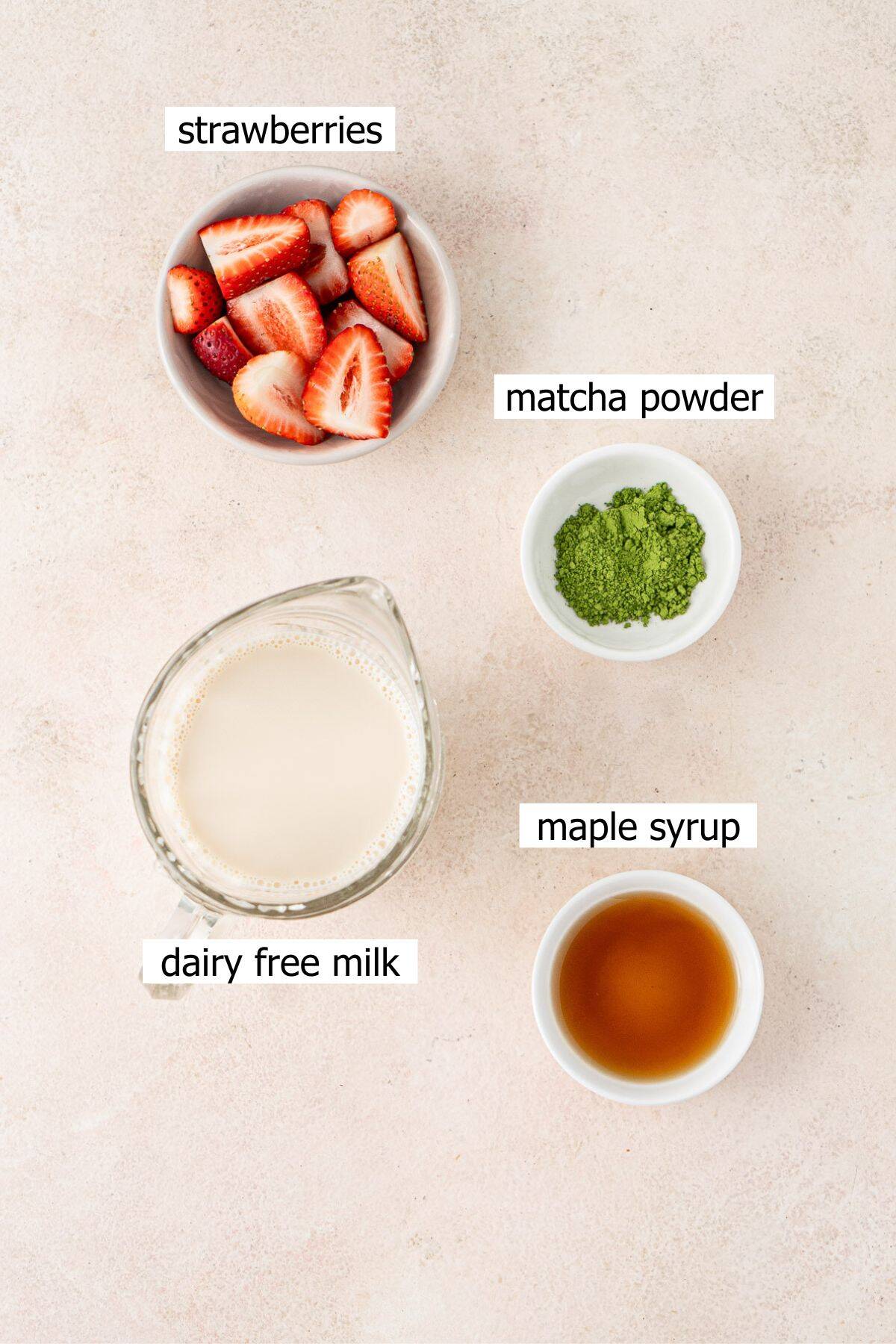 All ingredients needed to make a strawberry matcha latte laid out in bowls.