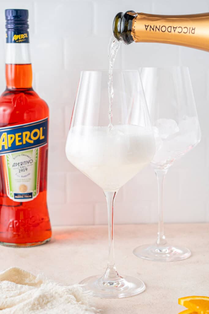 Pouring prosecco into a glass with ice.