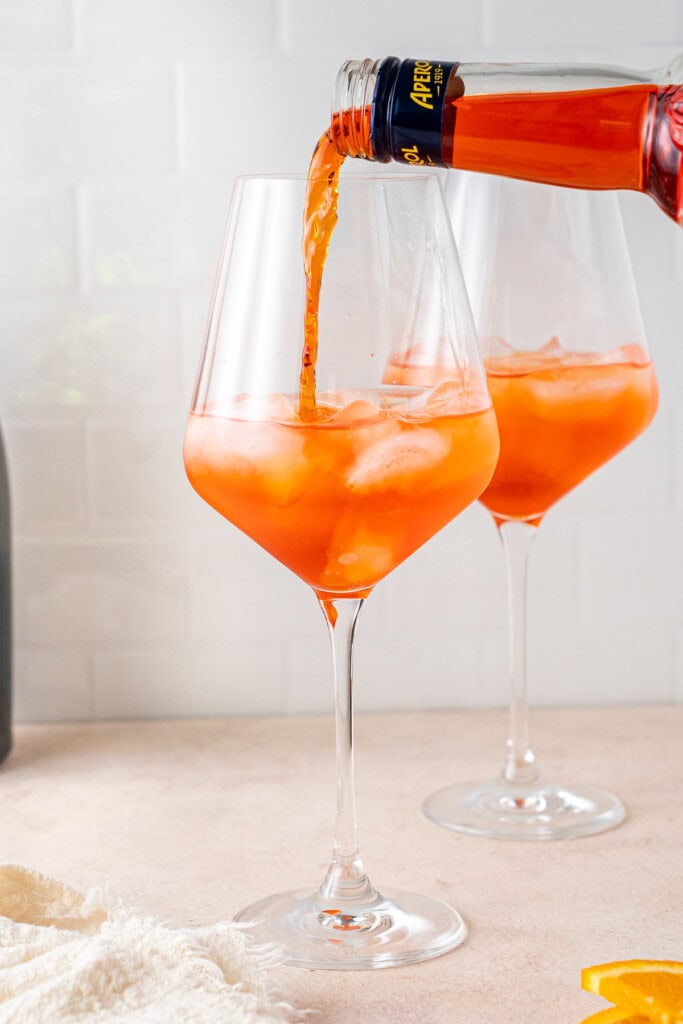 Pouring aperol into the glass.