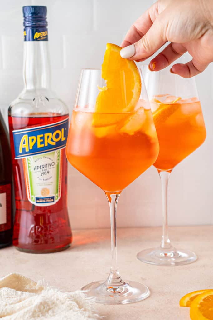 Adding a slice of orange to the glass.