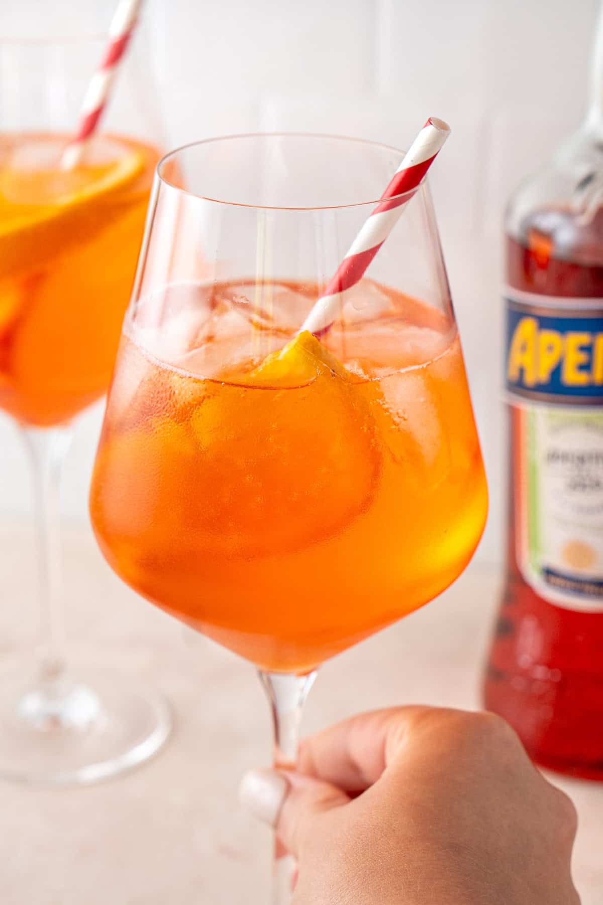 Close up of an aperol spritz with a straw.
