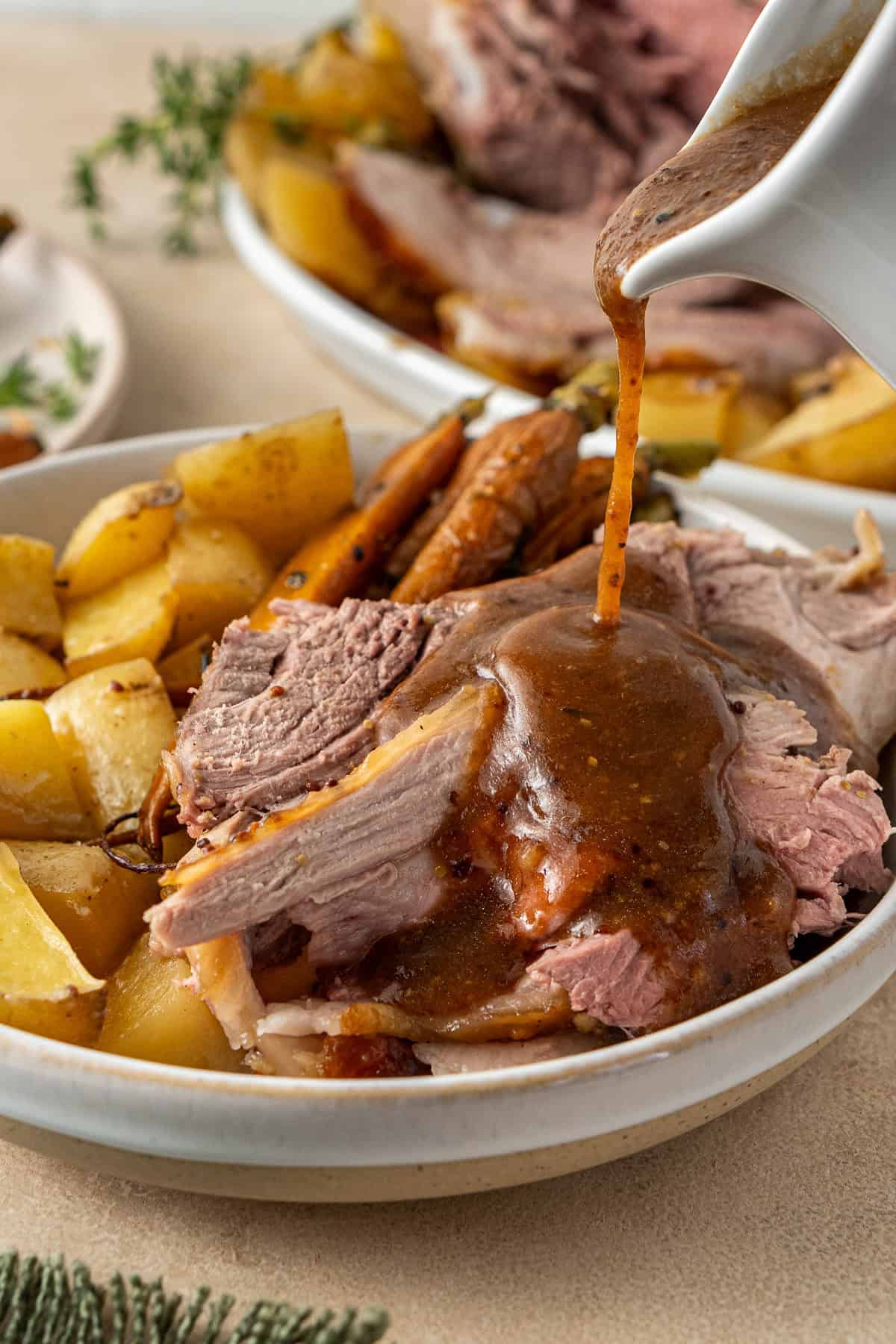 Pouring gravy over the roast lamb.