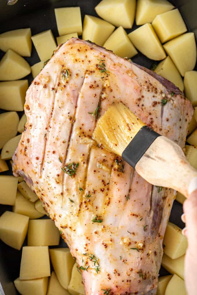 Brushing the lamb with the glaze.