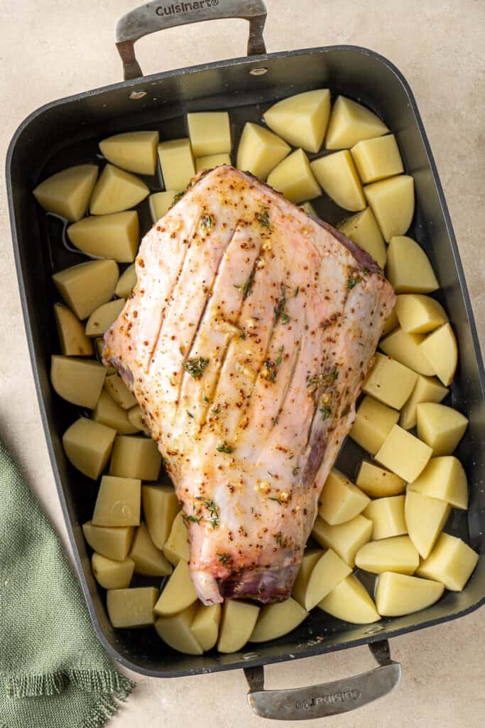 The roast lamb and potatoes in the baking dish ready for the oven.