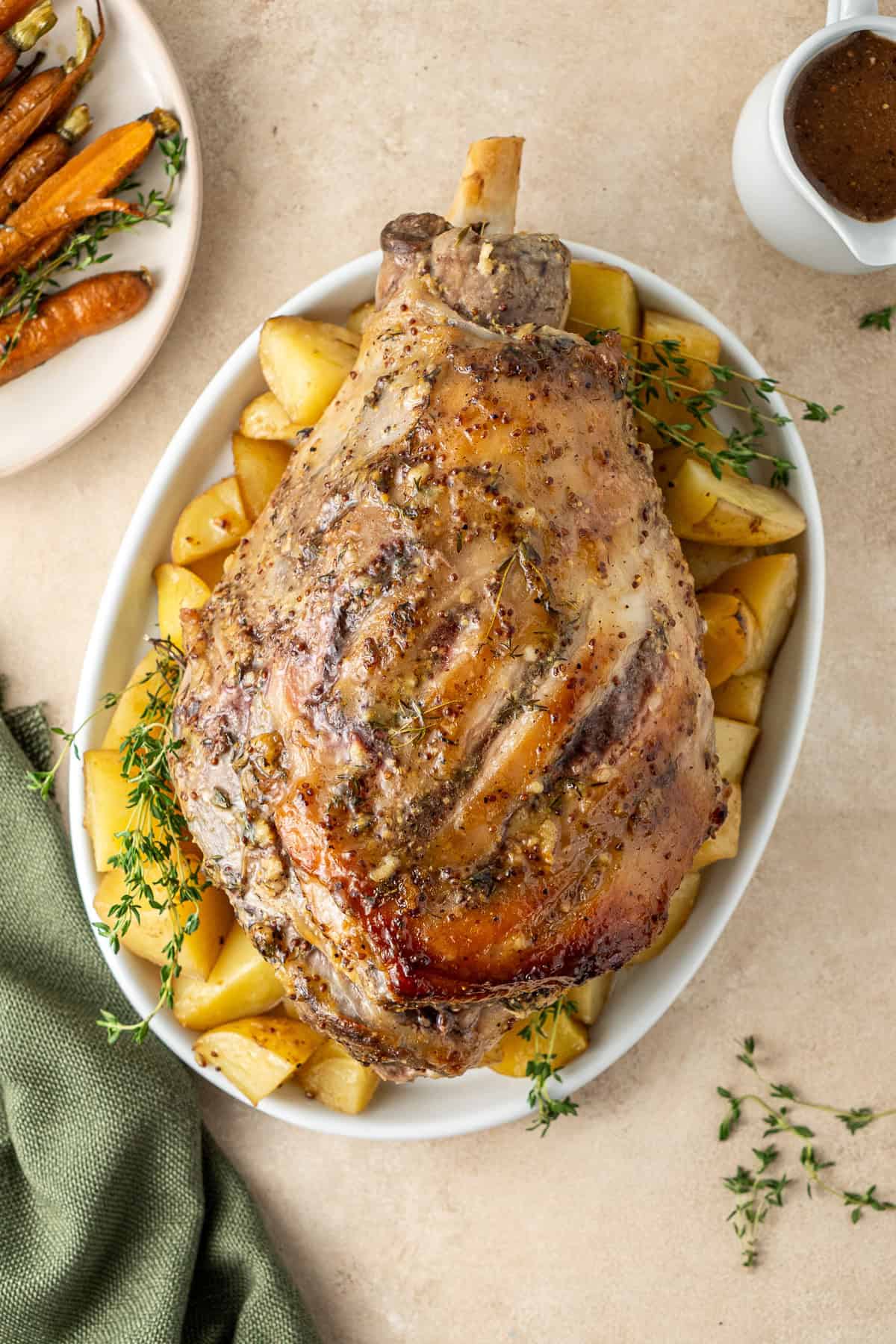 The glazed roast leg of lamb on a plate with potatoes.