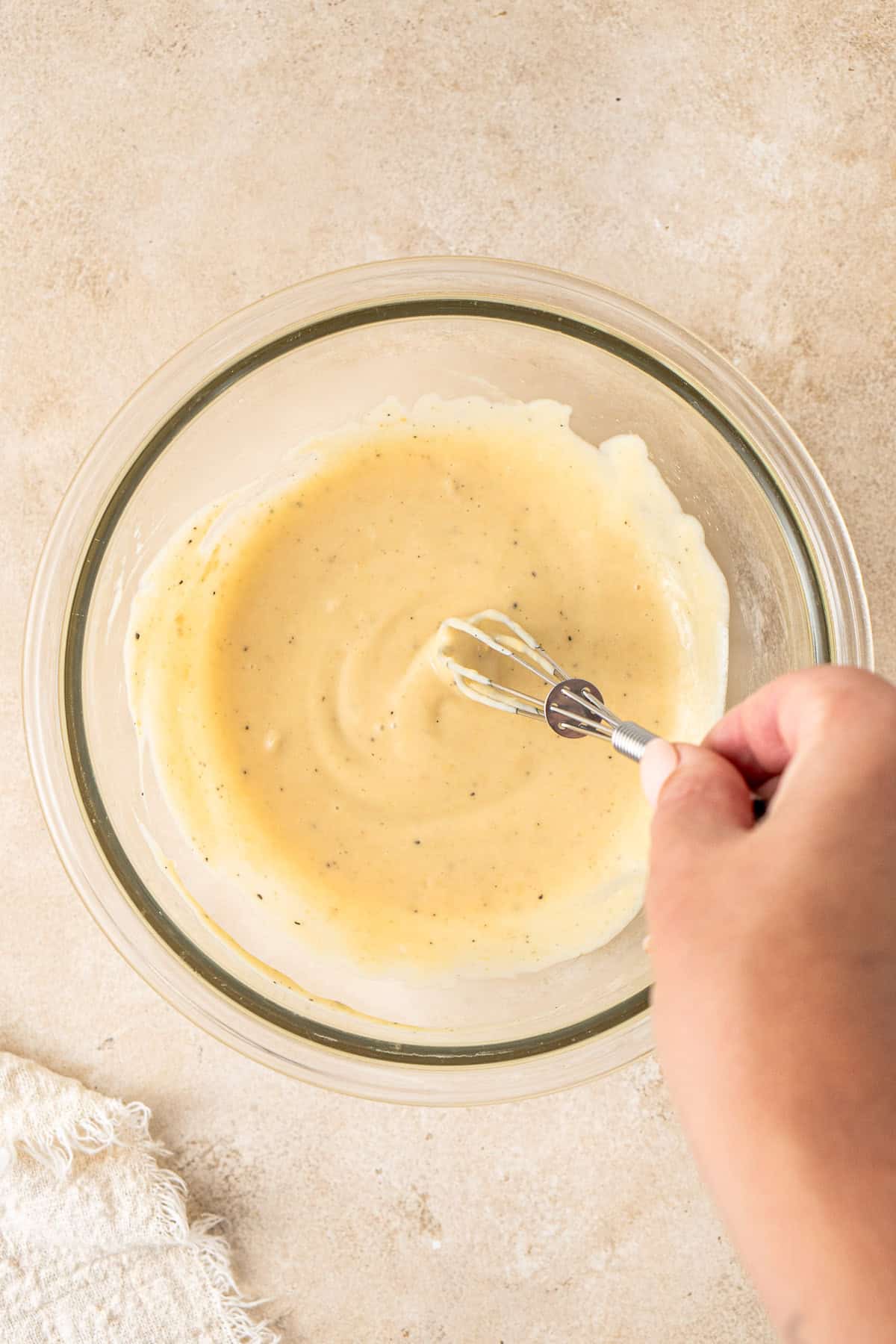 Whisking together the honey mustard sauce in a glass bowl.