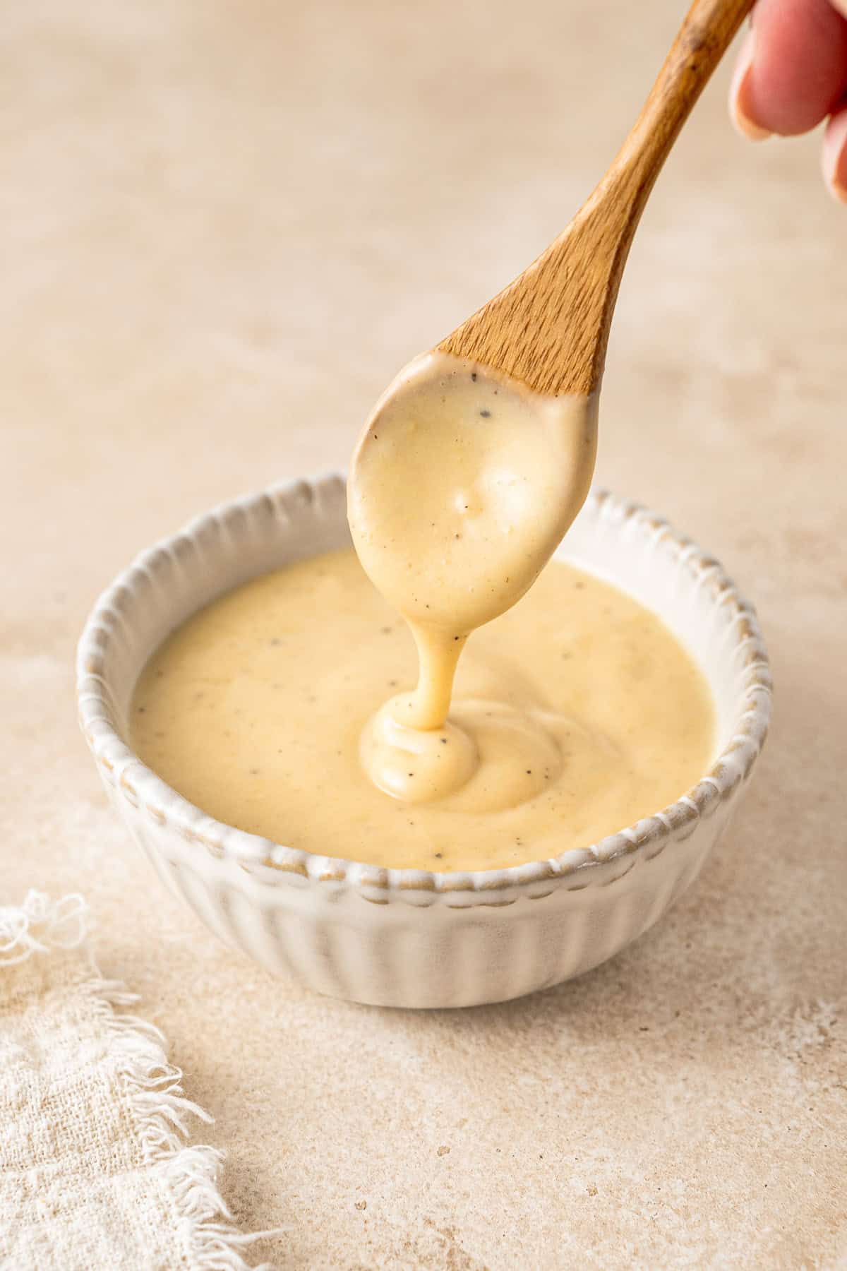 Drizzling honey mustard sauce from a spoon into a bowl.