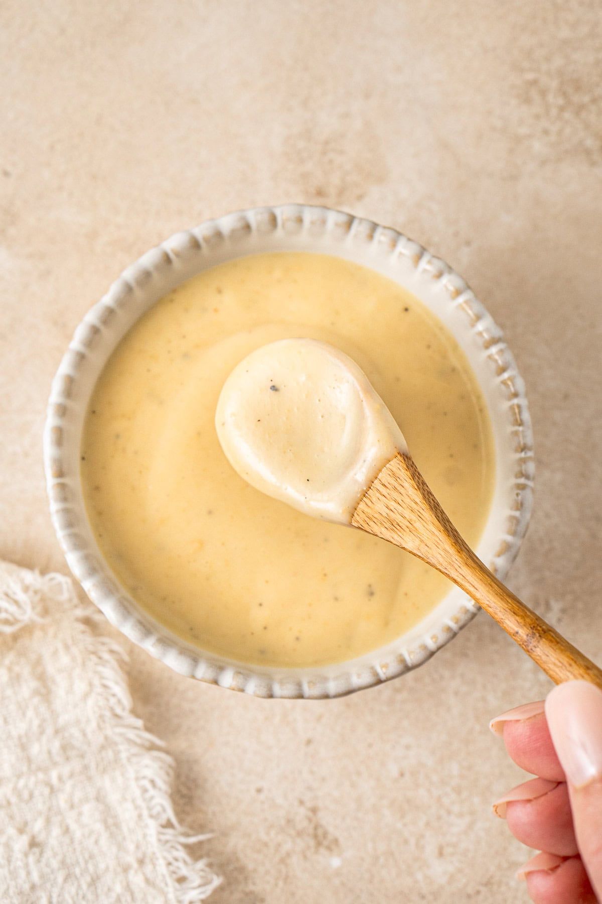 A spoon scooping up the honey mustard from a small bowl.